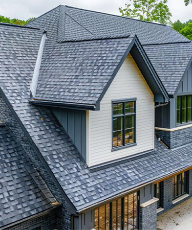 Dark gray shingled roof on a house with white and gray accents, black framed windows.