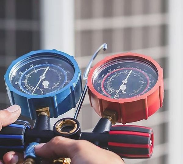 A person is holding two pressure gauges in their hand