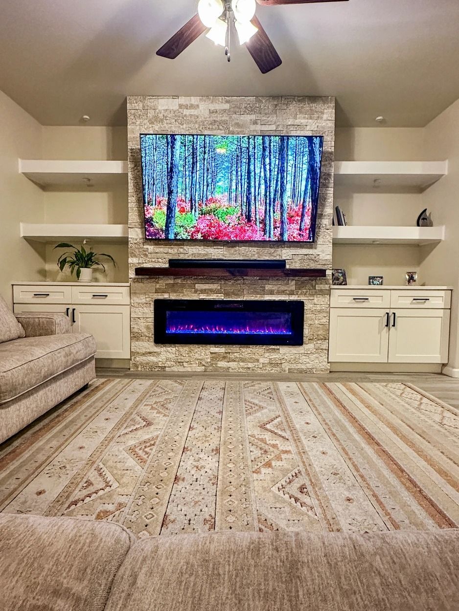 A living room with a fireplace and a flat screen tv on the wall.