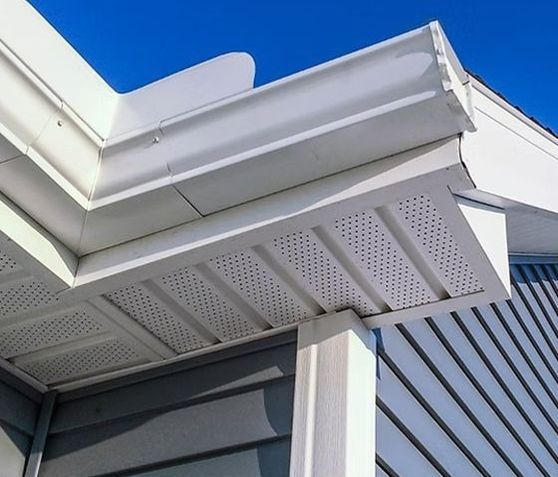 A white gutter on the side of a house with a blue sky in the background