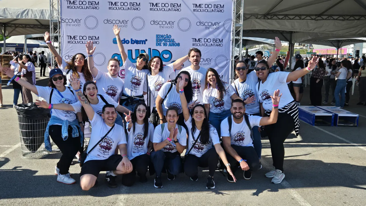 Grupo de dançarinos sorridentes posando ao ar livre com camisas azul-claras combinando em um evento de apresentação.