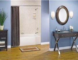 A bathroom with a sink , mirror and bathtub.