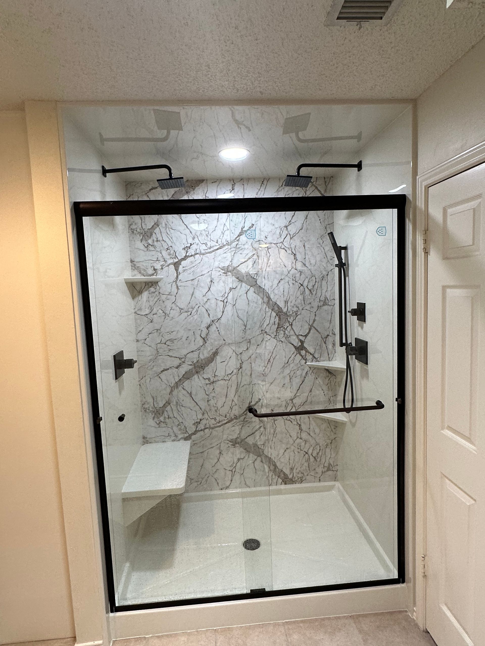 A bathroom with a walk in shower with a sliding glass door.