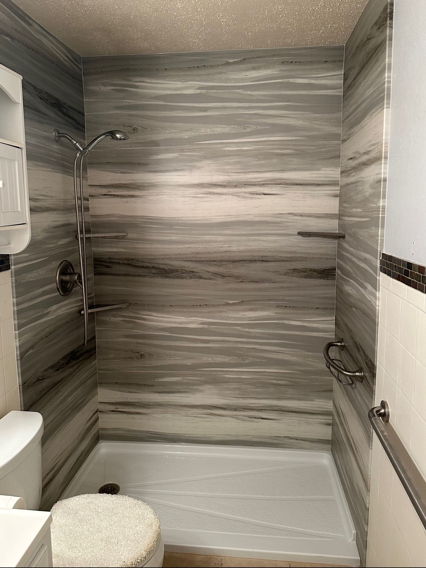 A bathroom with a shower , toilet and sink.