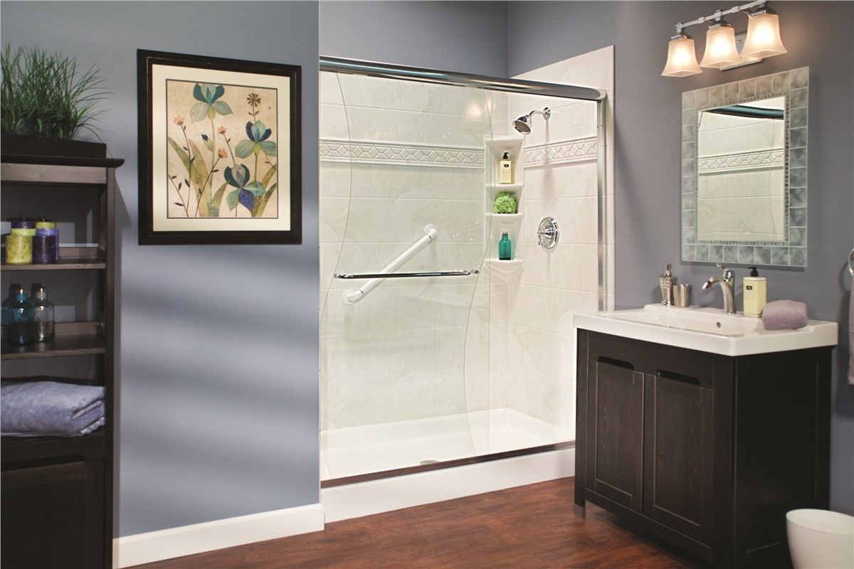 A bathroom with a shower , sink , mirror and picture on the wall.