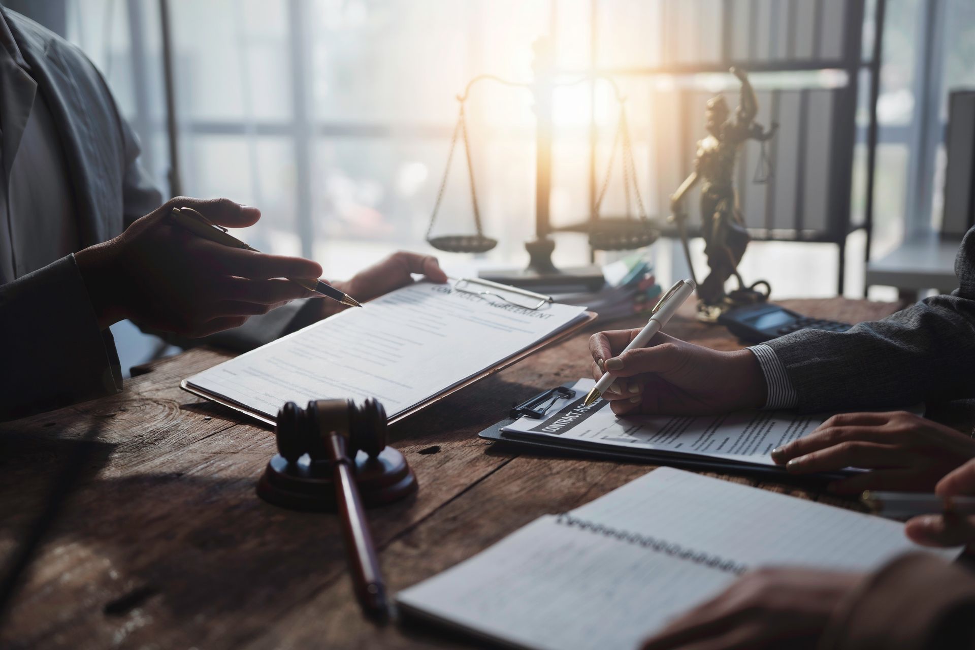 Lawyers working on a legal document with a gavel and scales of justice in the table.