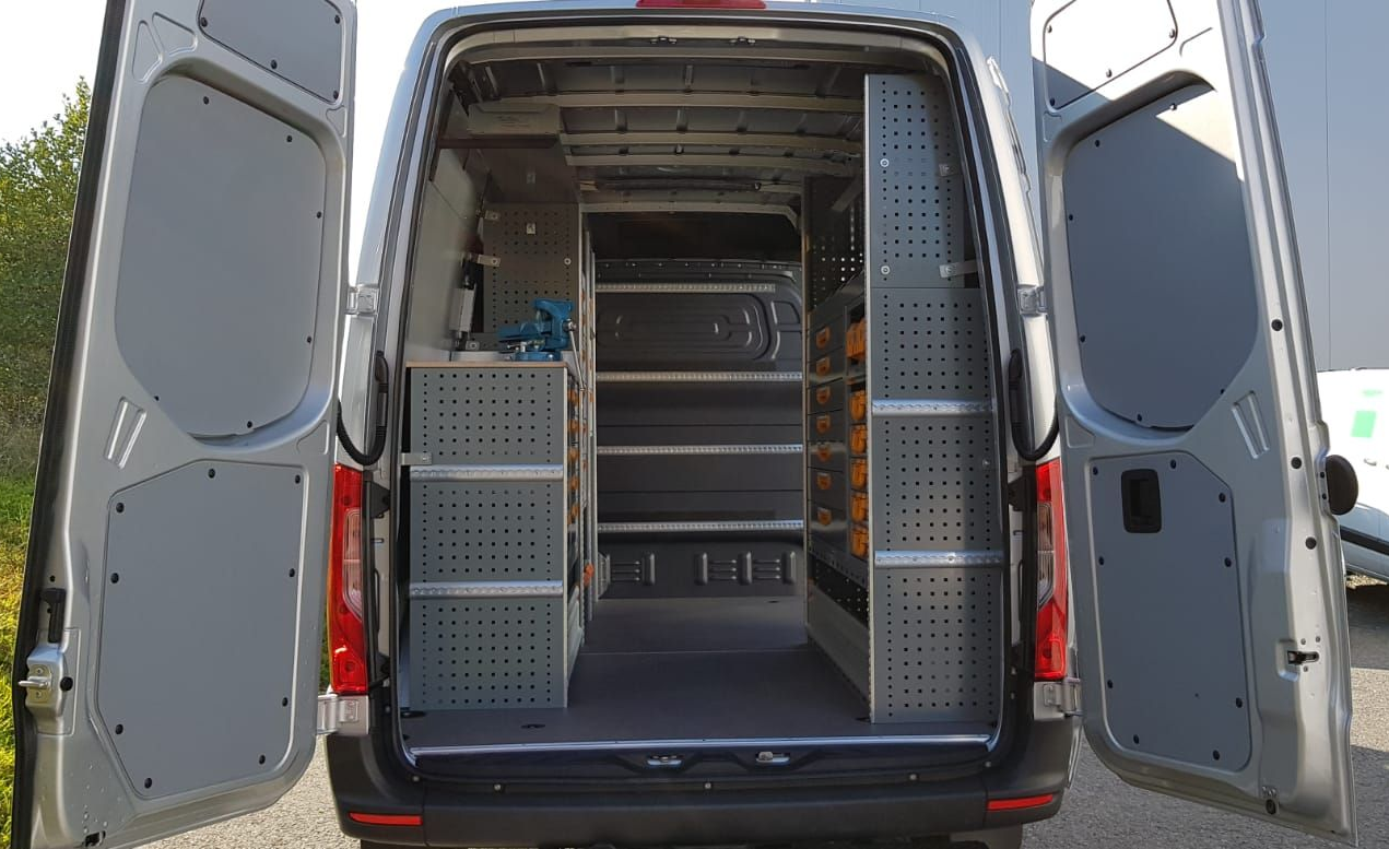 Rückansicht eines silbernen Lieferwagens mit offenen Türen, der im Inneren Regale für Werkzeuge zeigt.