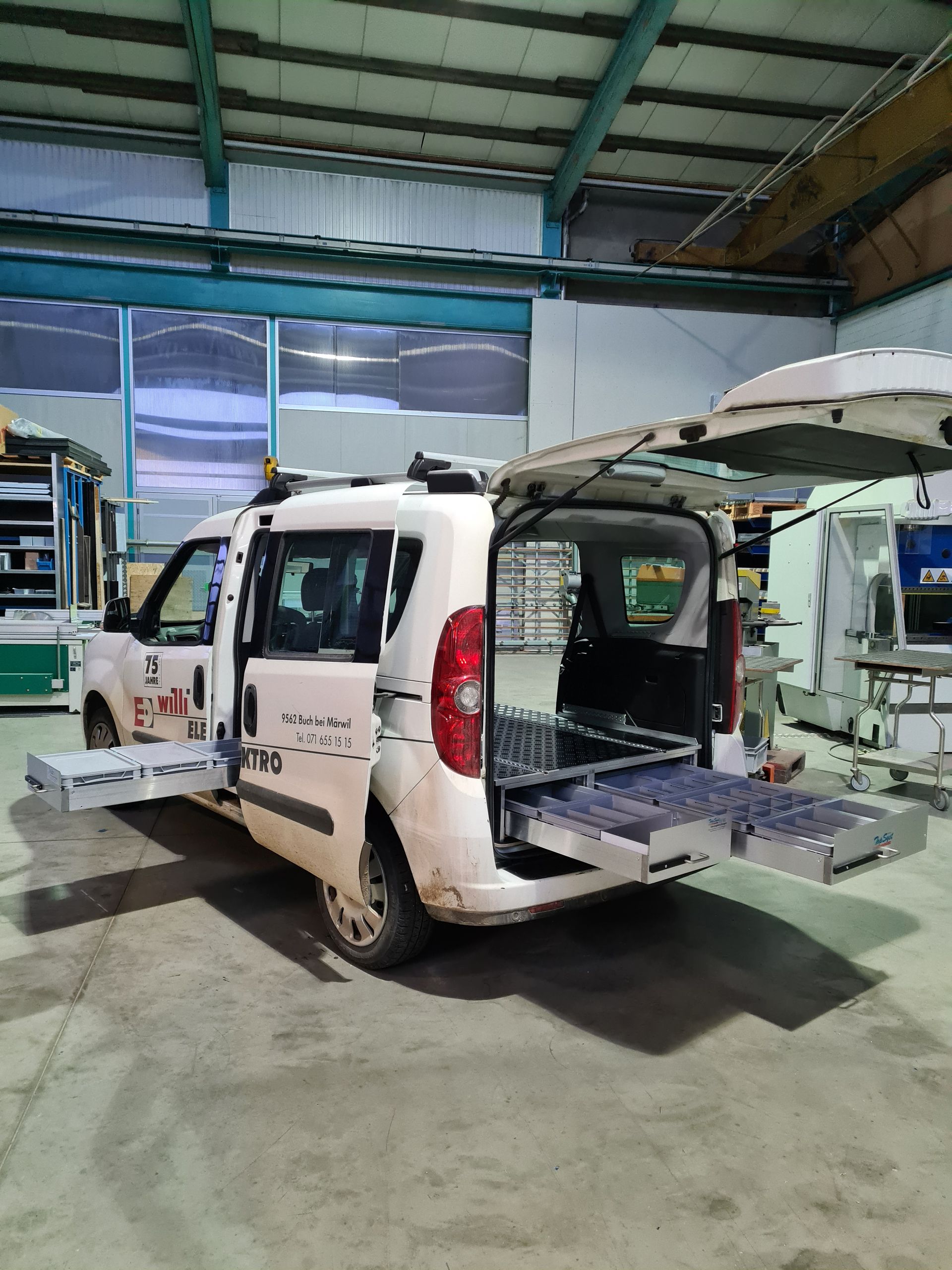 Weißer Servicewagen mit offenen seitlichen und hinteren Schubladen in einer Werkstatt.