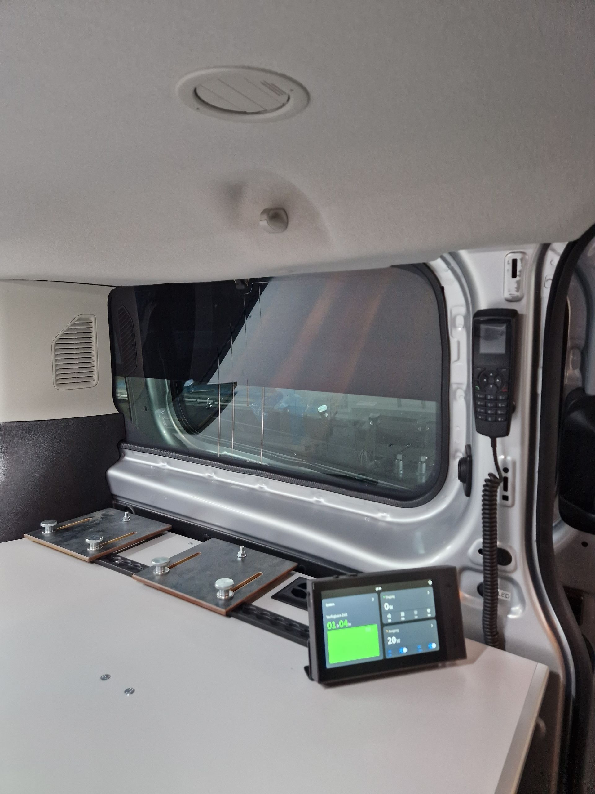 Innenraum eines Lieferwagens mit Monitor, Fenster und Ausstattung; scheint als Wohnmobil umgebaut zu sein.