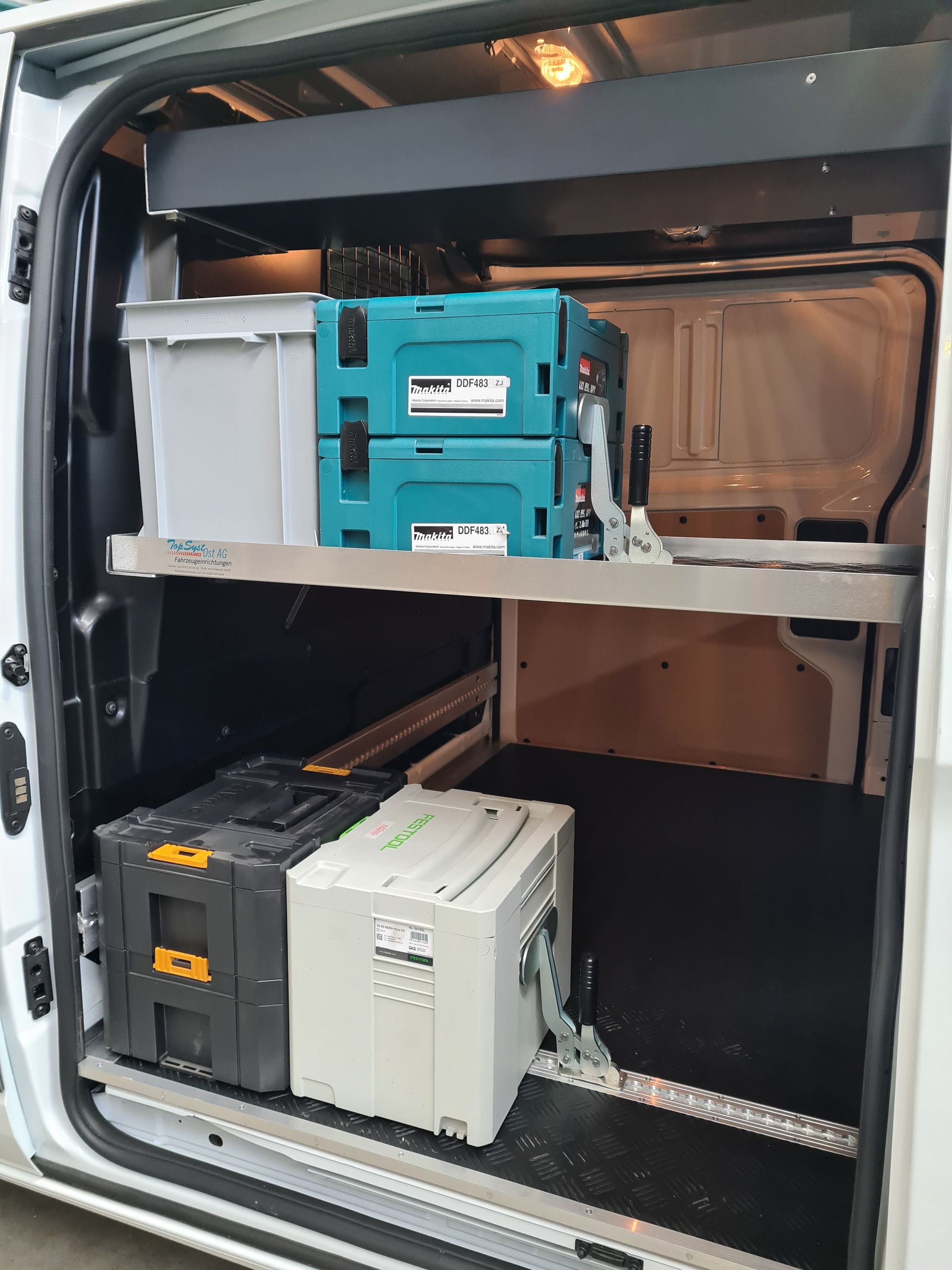 Innenraum des Lieferwagens mit Regalen für Werkzeugkästen und Lagerbehälter.