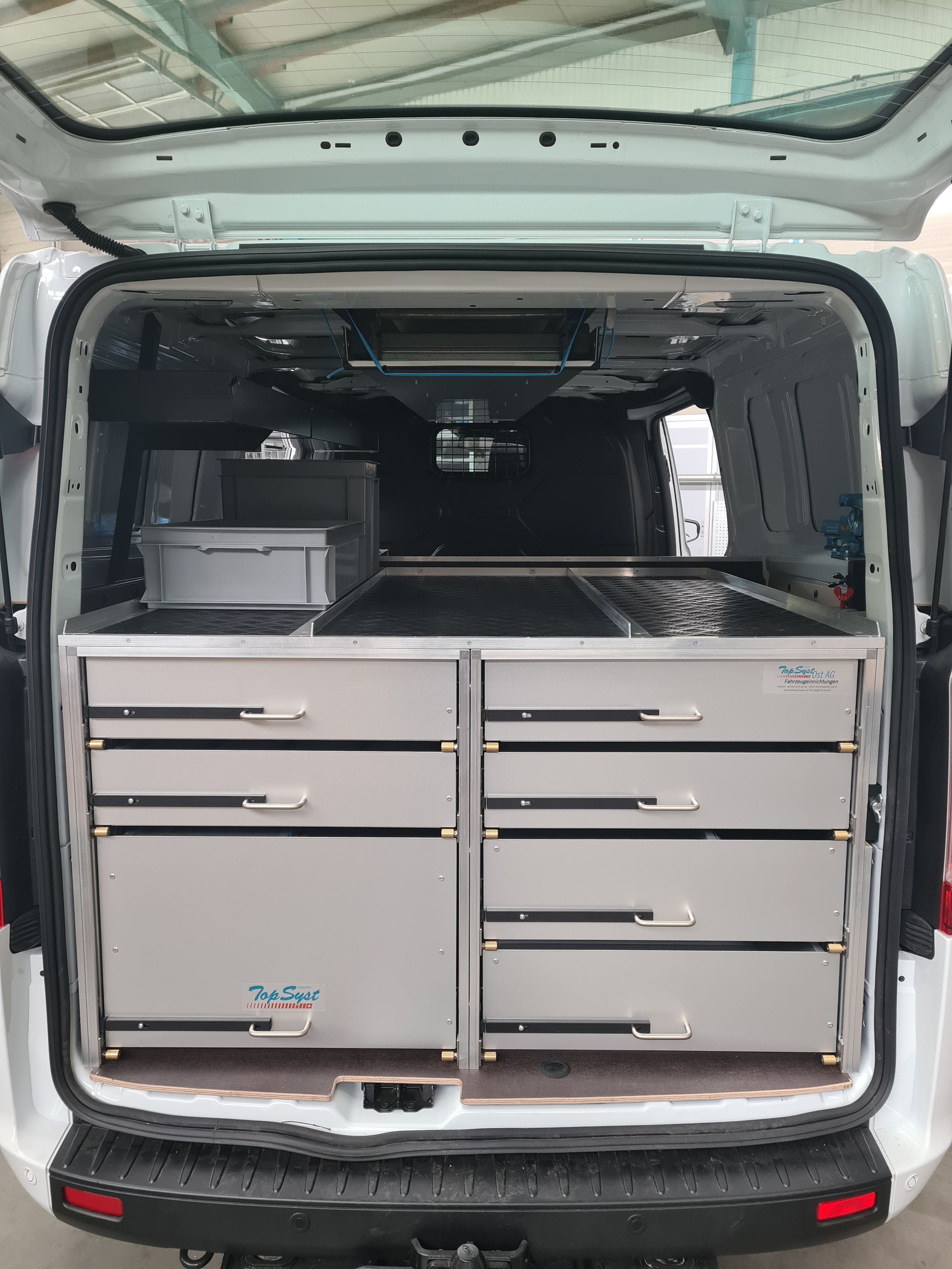 Innenraum eines weißen Lieferwagens mit Schubladen und Staufächern aus Metall.