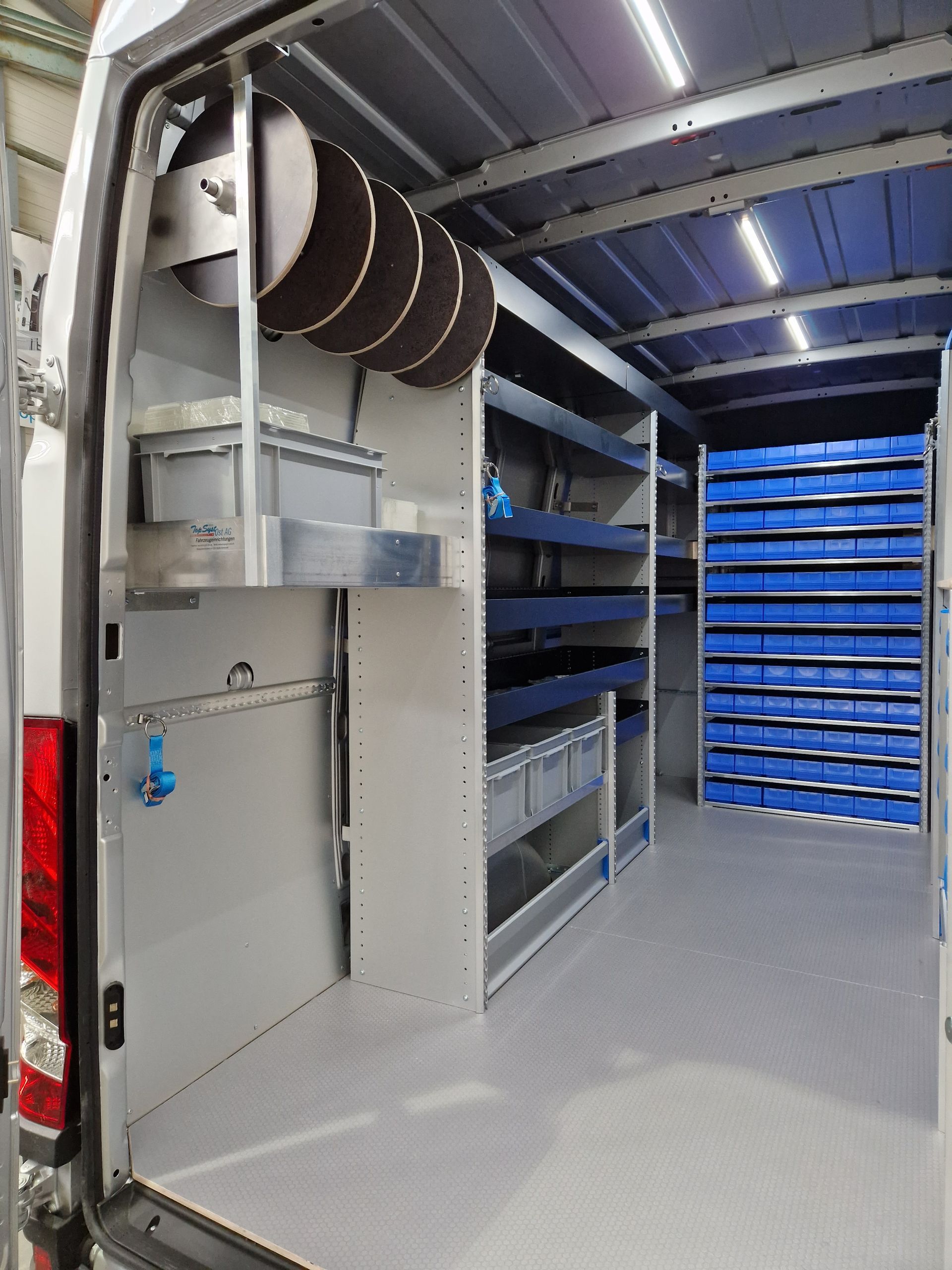 Innenansicht eines Arbeitstransporters mit Regalen und Lagerbehältern, gefüllt mit Werkzeugen und Vorräten.