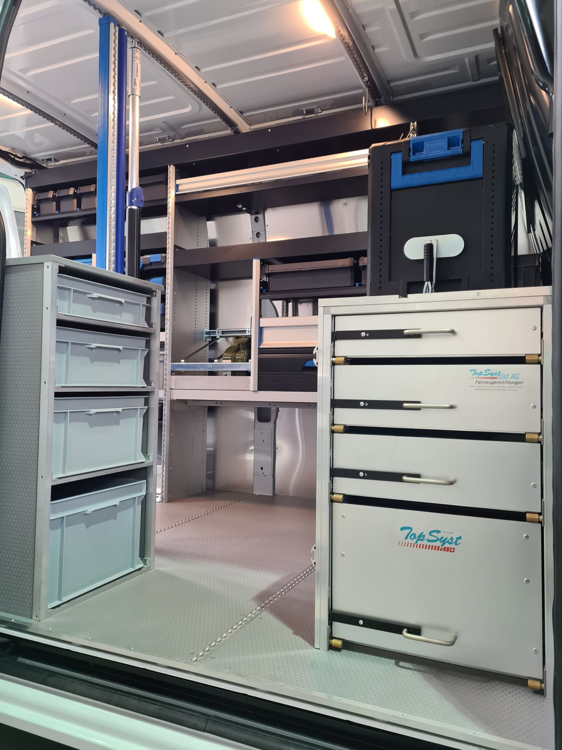 Innenansicht eines Servicewagens mit Regalen, Schubladen und geordneten Werkzeugen.