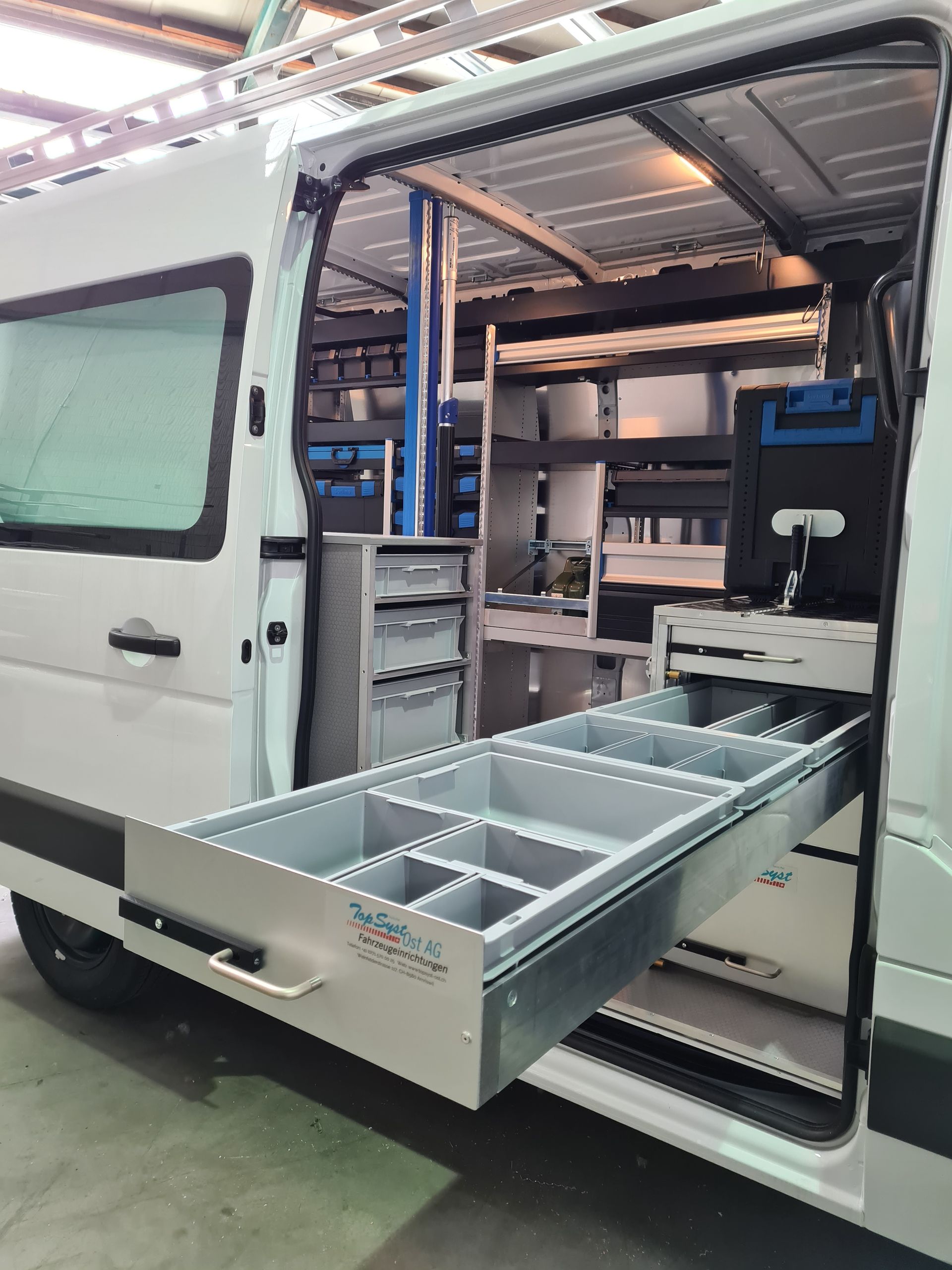 Weißer Lieferwageninnenraum mit offener Schublade, gefüllt mit Fächern.