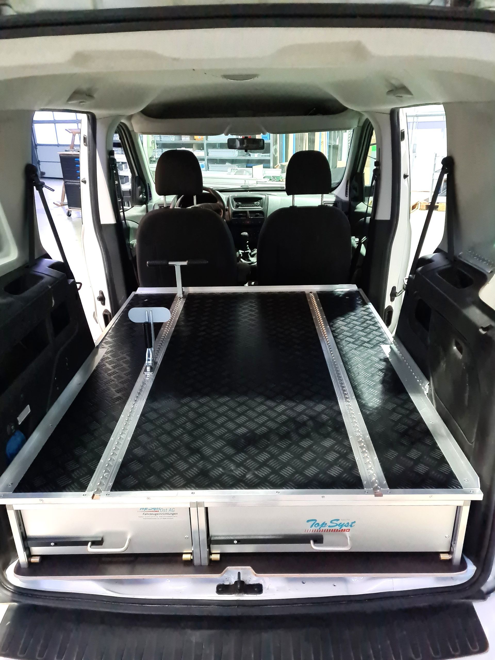 Innenraum eines weißen Fahrzeugs mit einem Aufbewahrungssystem mit einer Diamantplattenoberfläche.