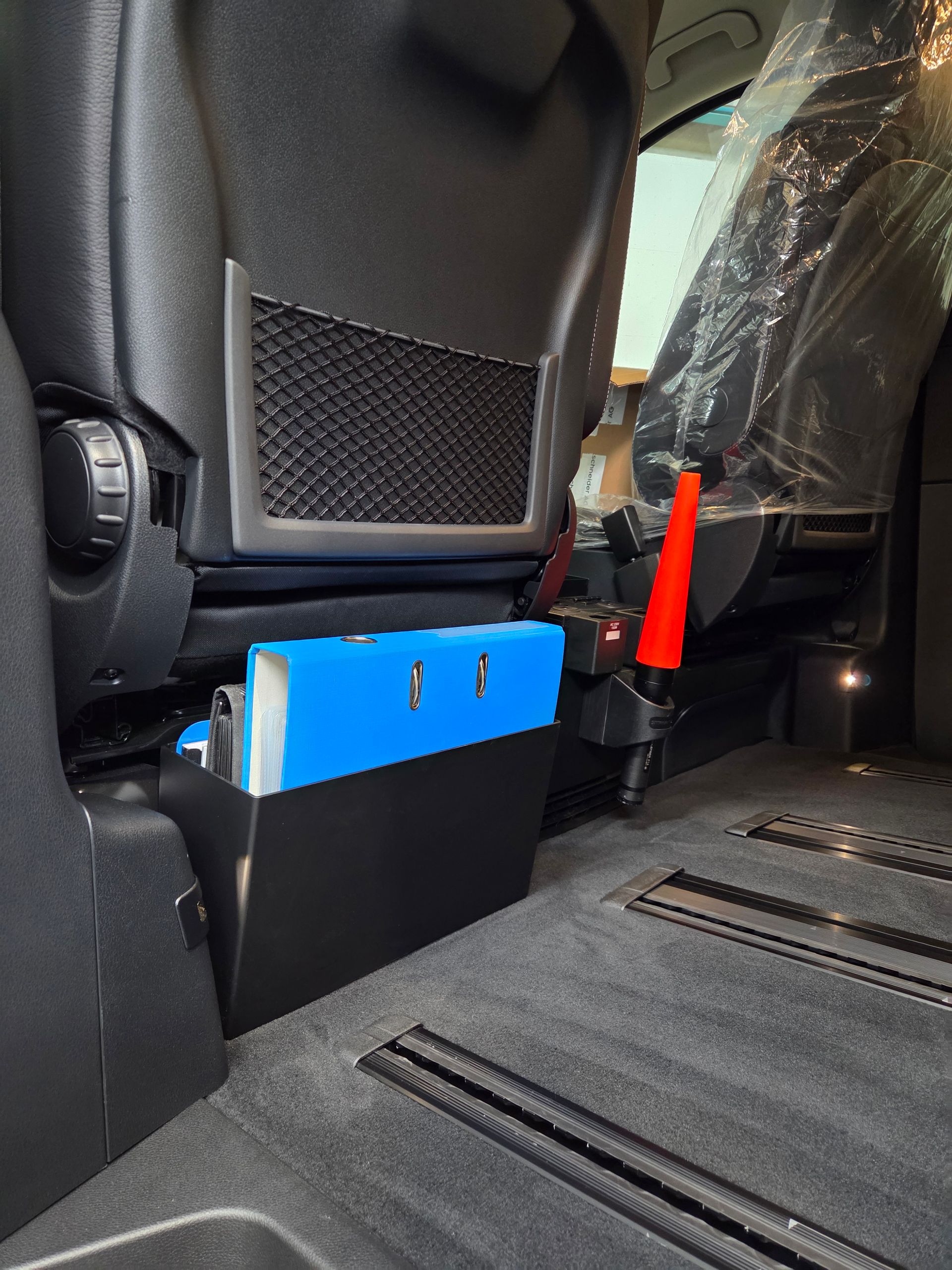 Schwarze Autositzbasis mit blauer Aufbewahrungsbox im Fahrzeuginnenraum.