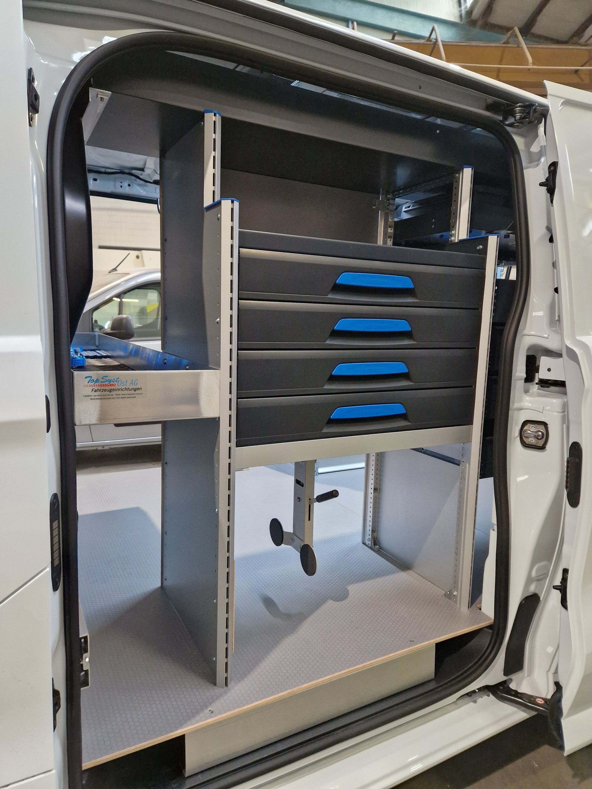 Weiße Van-Innenausstattung mit eingebauten Regalen und Schubladen; grau und schwarz.