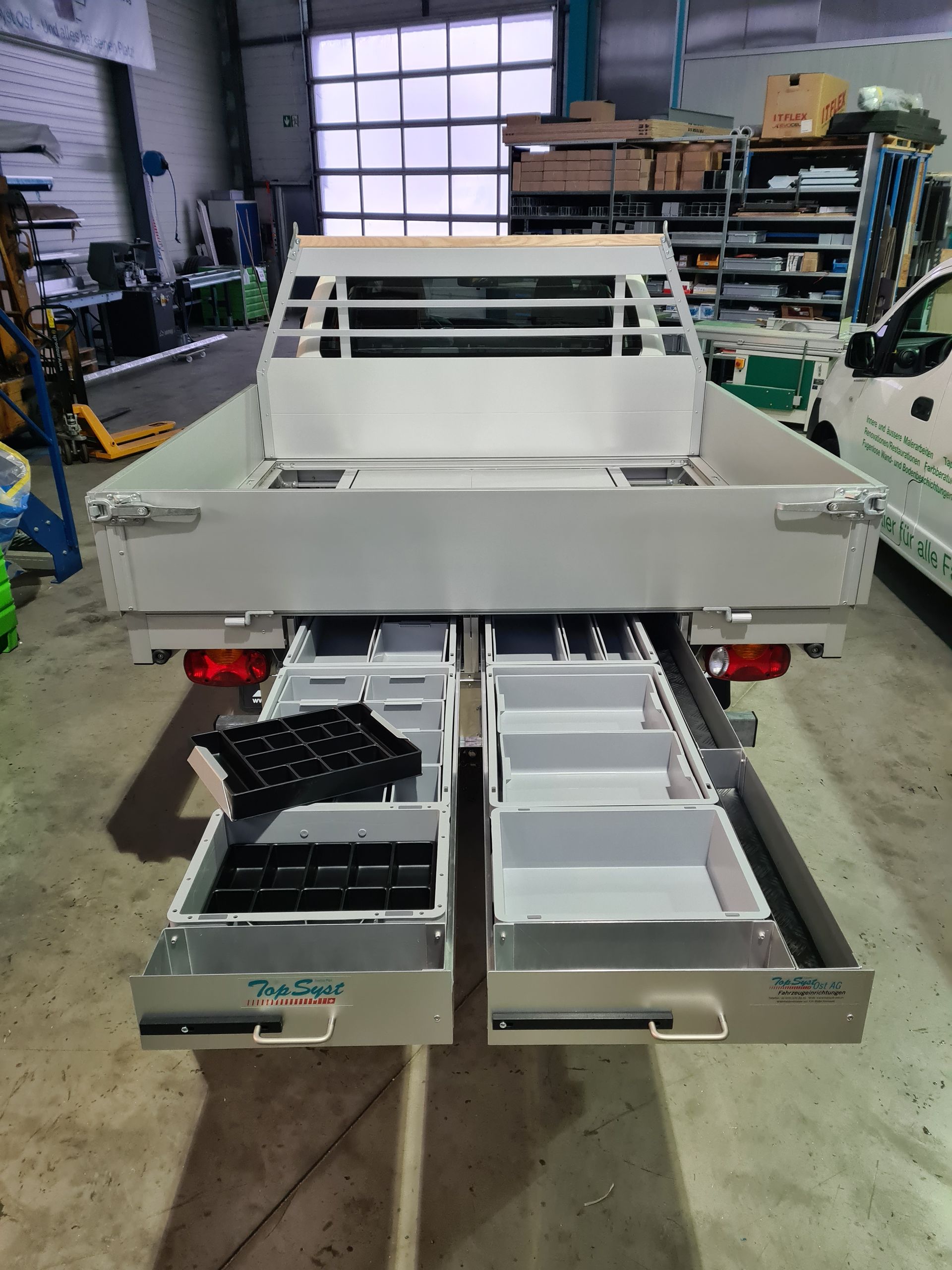 Ladefläche aus Aluminium mit zwei offenen Schubladen voller Werkzeuge und Teile.