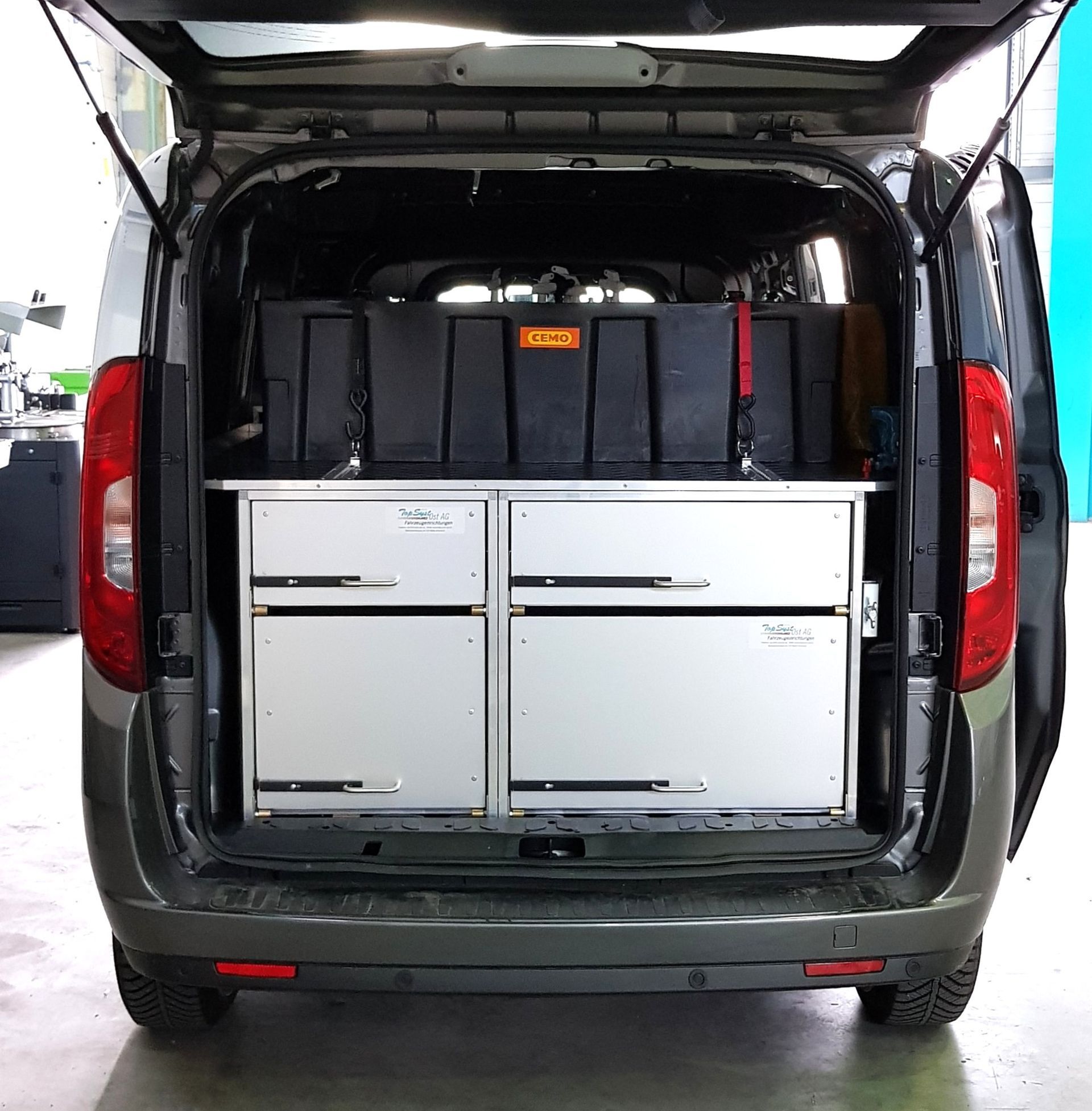 Im Inneren eines grauen Lieferwagens befindet sich ein Lagerschrank mit Schubladen und schwarzen Aufbewahrungsboxen.