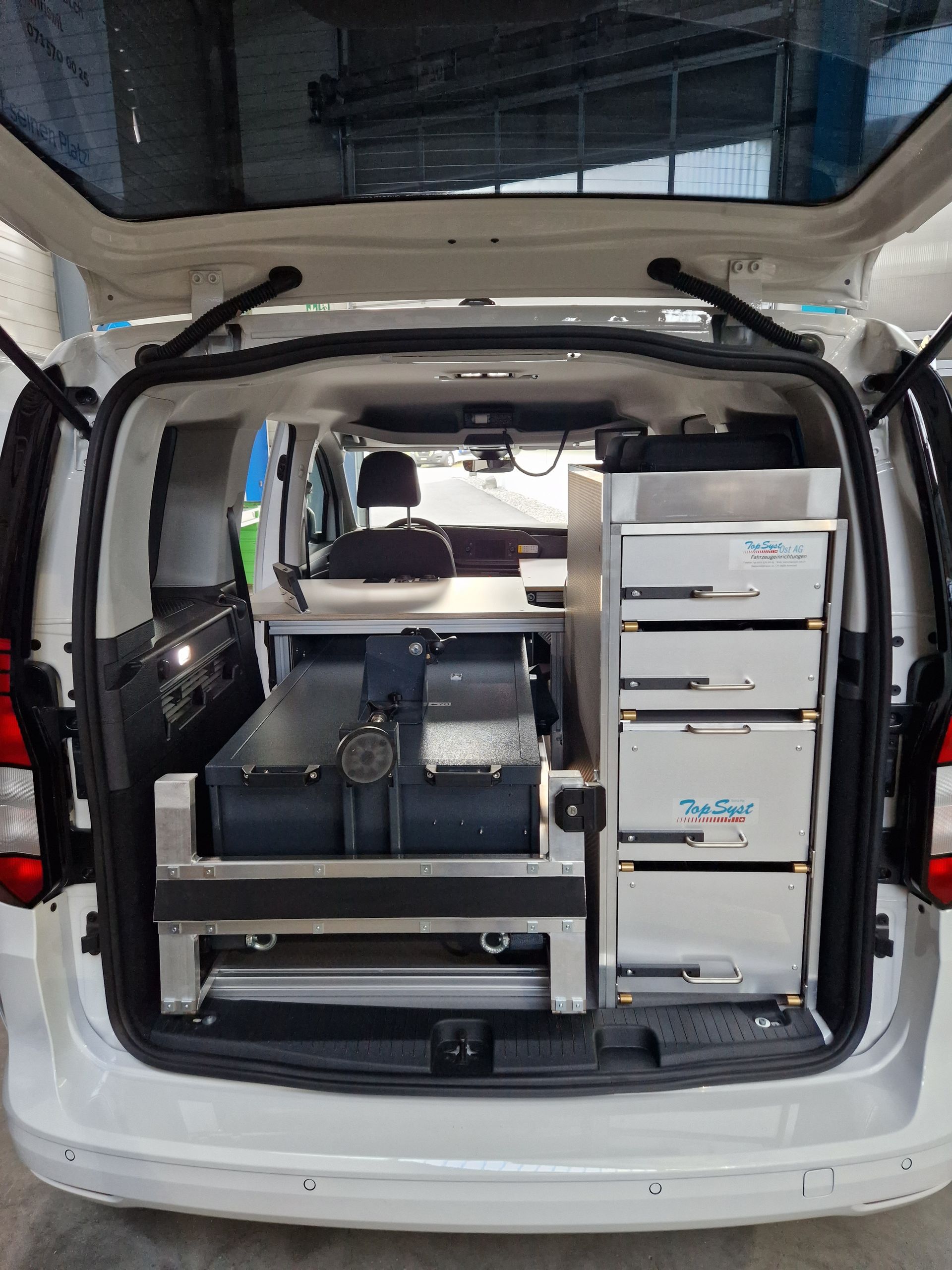 Offene Ladefläche eines weißen Lieferwagens, ausgestattet mit wissenschaftlicher Ausrüstung in einer laborähnlichen Umgebung.