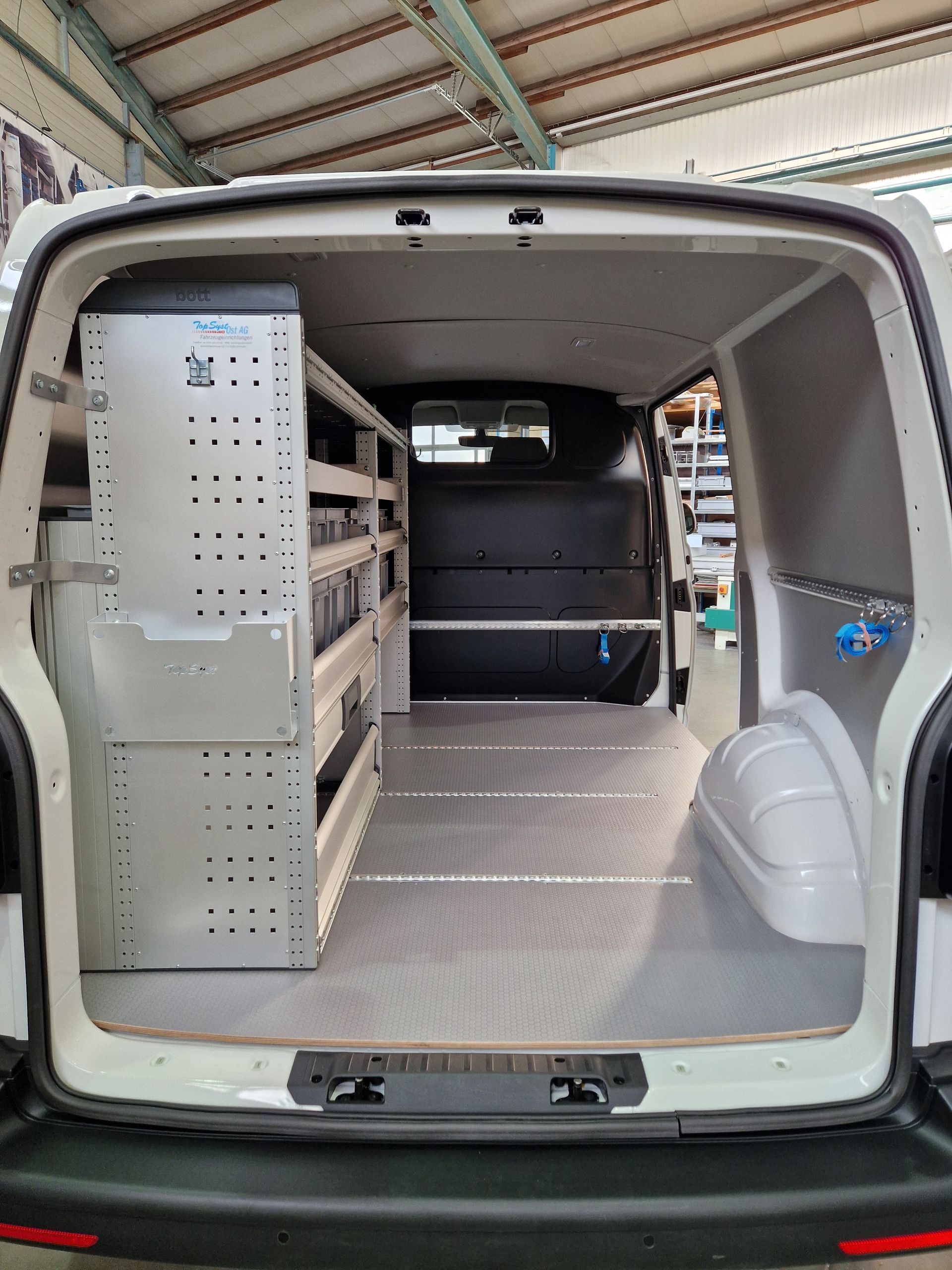 Freier Blick in den Innenraum eines weißen Lieferwagens mit Regalen und grauem Boden.