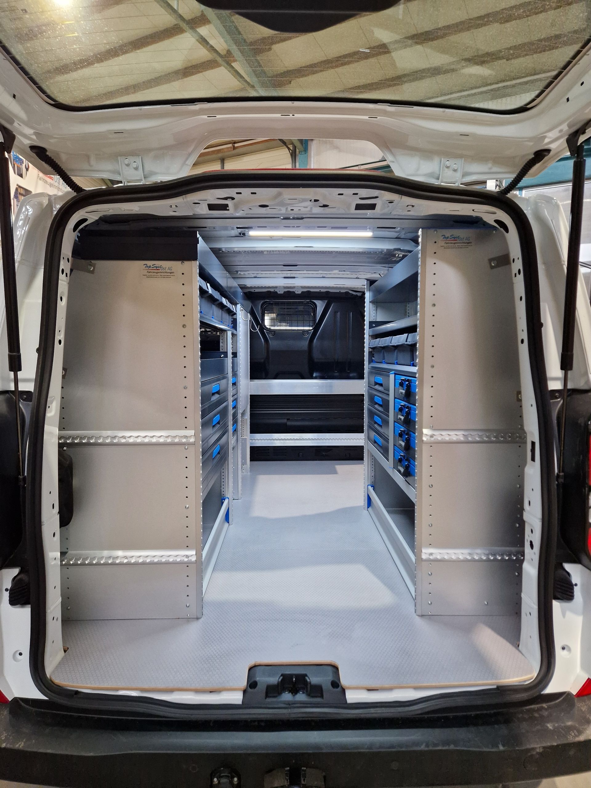 Weißer Van-Innenraum mit Regalen und Staufächern, beleuchtet.
