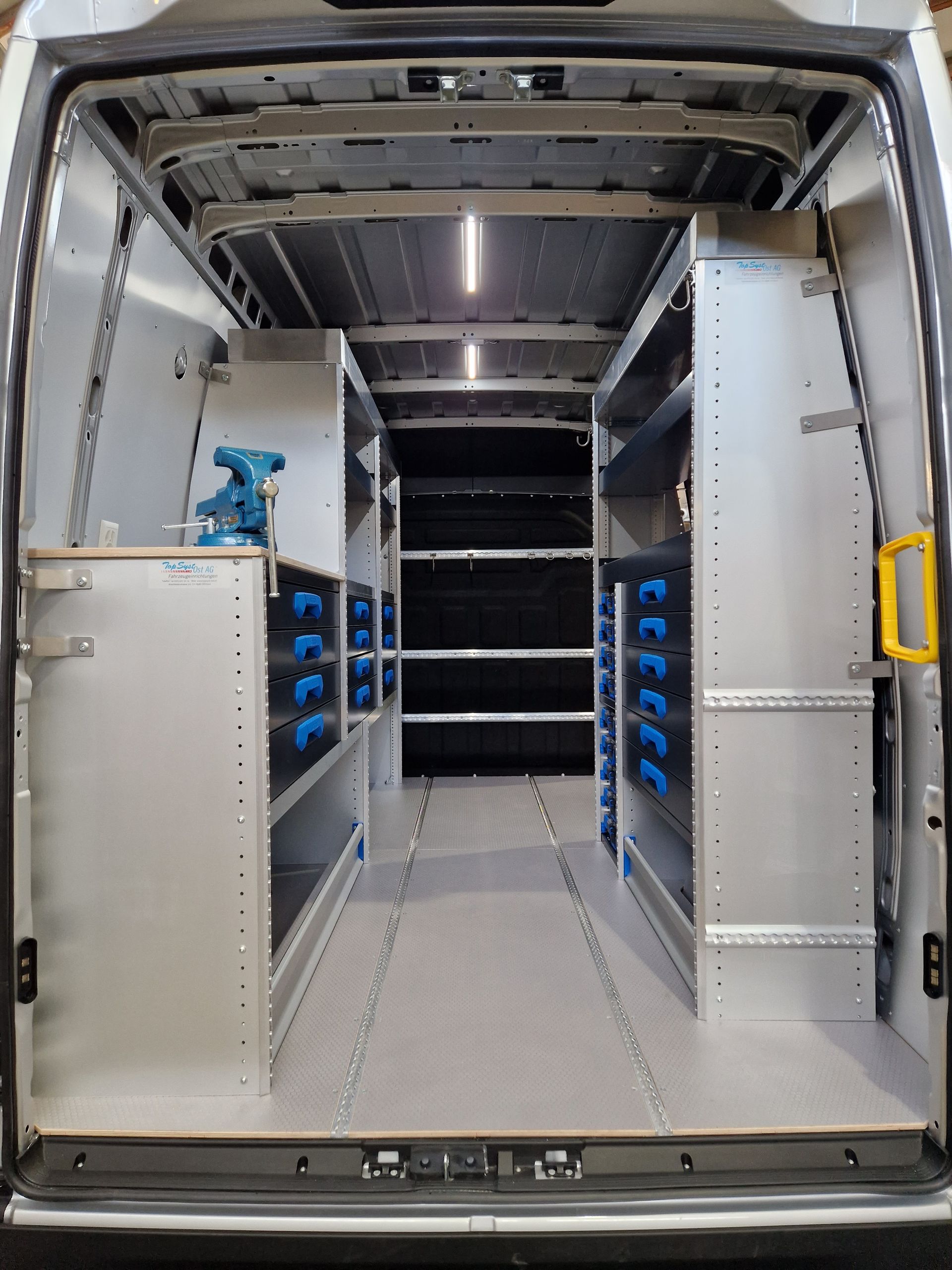 Im Inneren befindet sich ein Arbeitstransporter, ausgestattet mit Metallregalen und Schubladen für Werkzeuge und Ausrüstung.