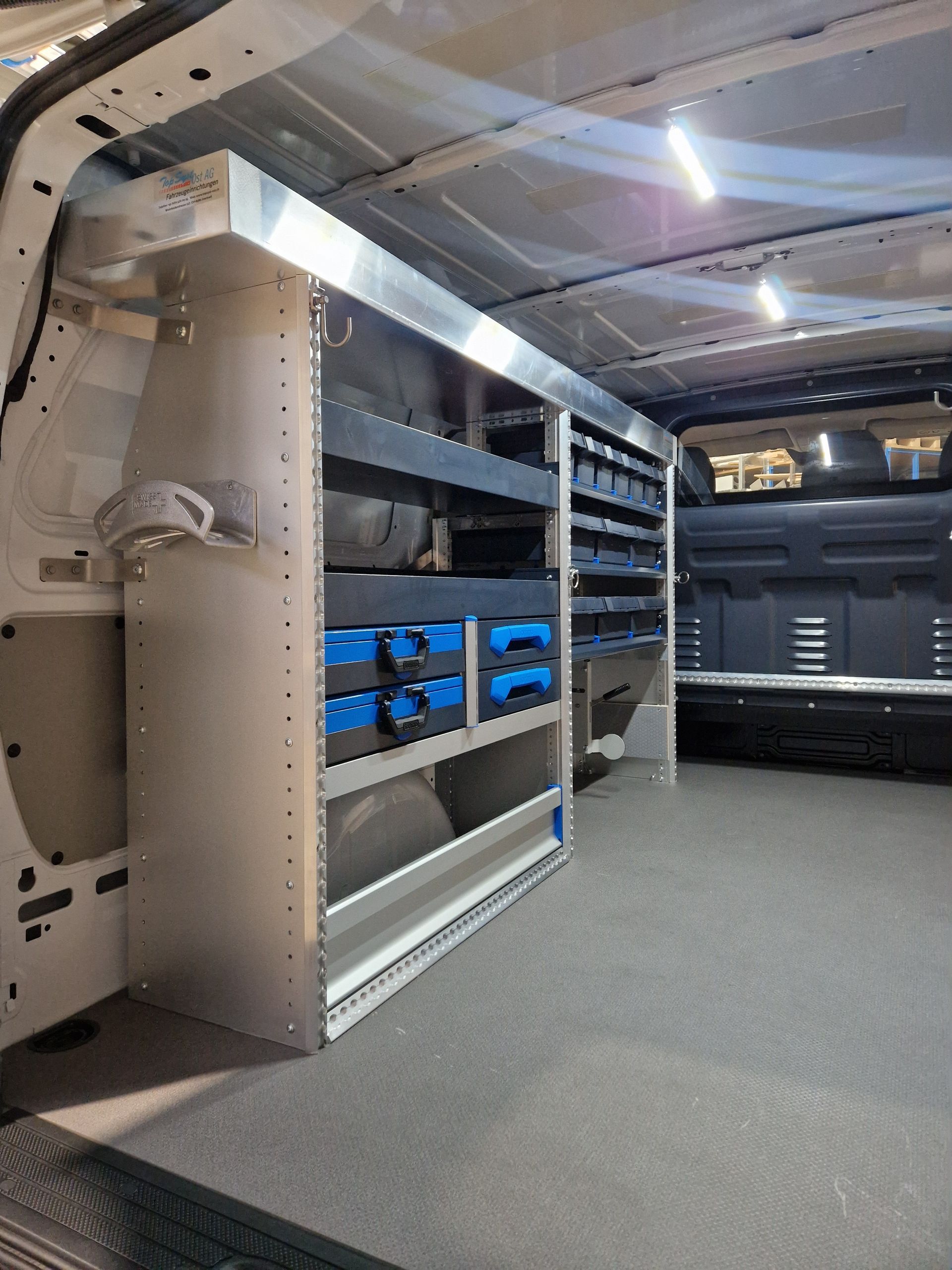 Innenansicht eines Arbeitstransporters mit maßgefertigten Regalen, Schubladen und geordneten Werkzeugen.