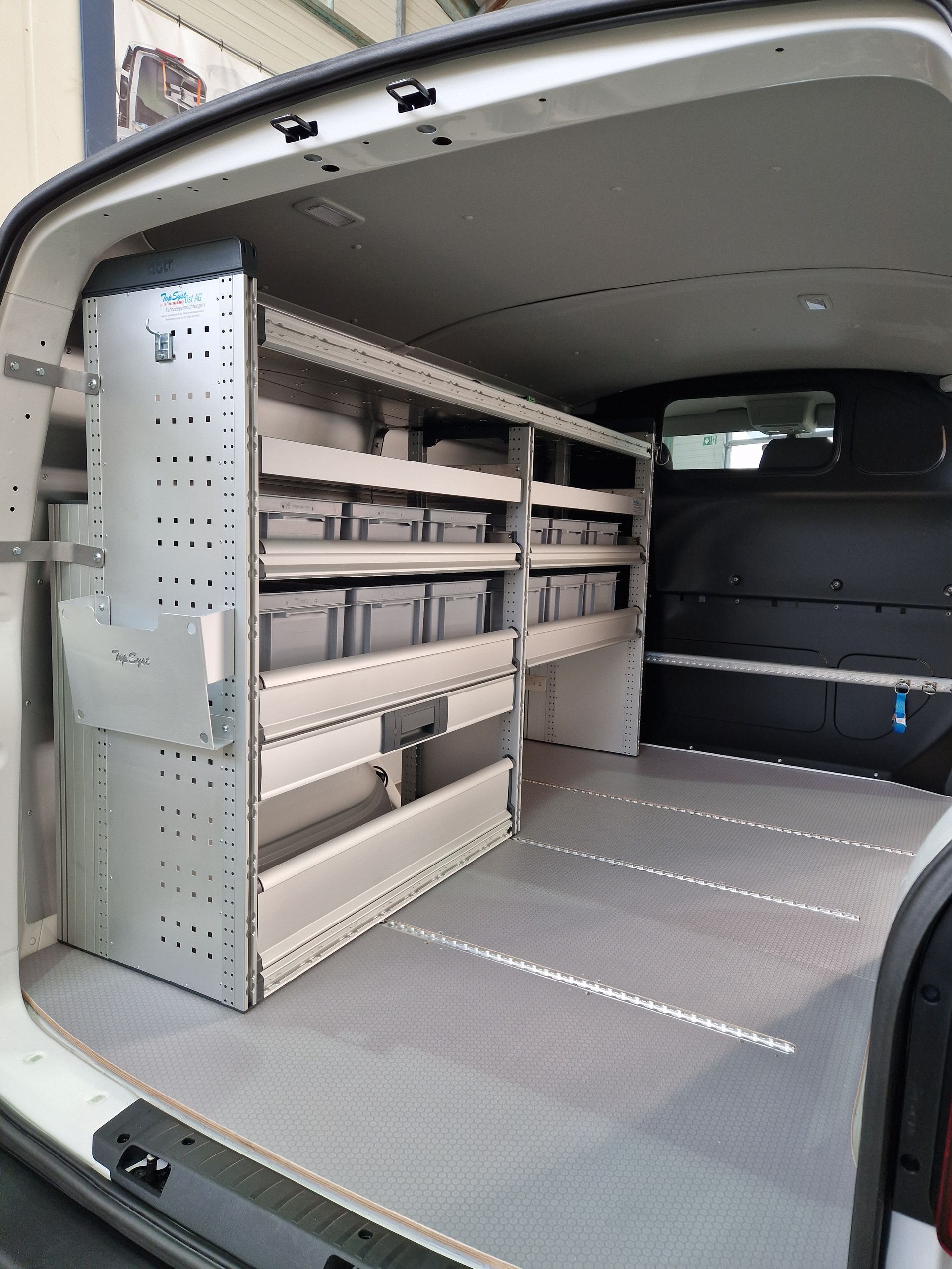 Innenraum eines weißen Lieferwagens mit Regalen und Staufächern; grauer Boden und Seiten.