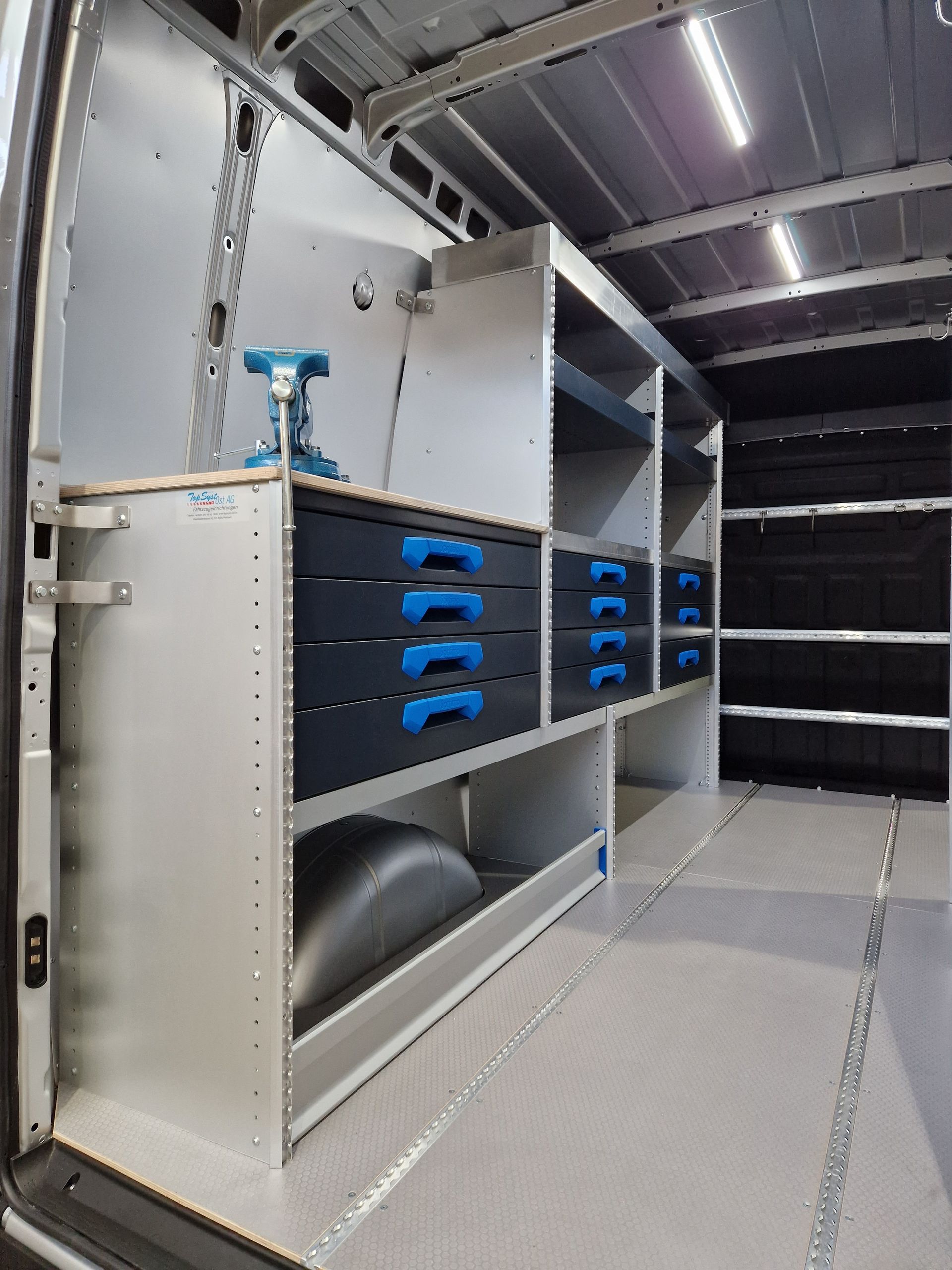 Innenraum eines weißen Lieferwagens mit maßgefertigten Regalen, Schubladen und Beleuchtung.