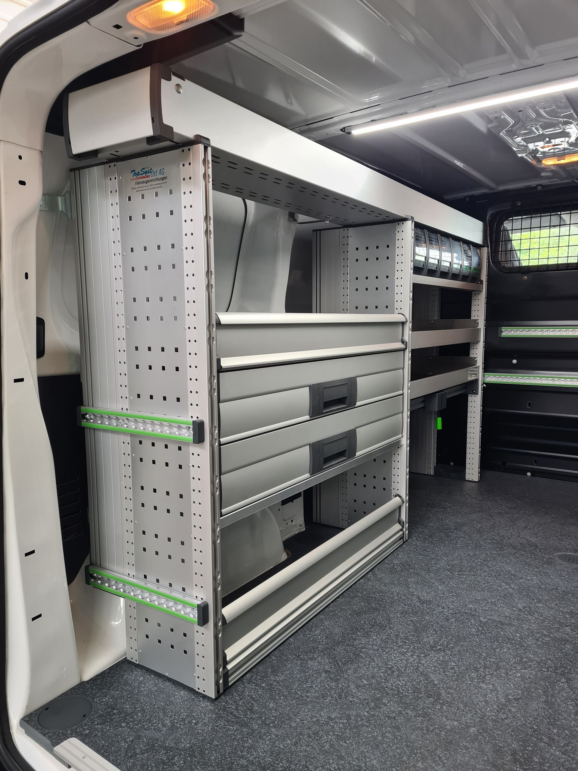 Im Inneren eines Lieferwagens: Graues Metallregal mit Schubladen und grünen Stützen.