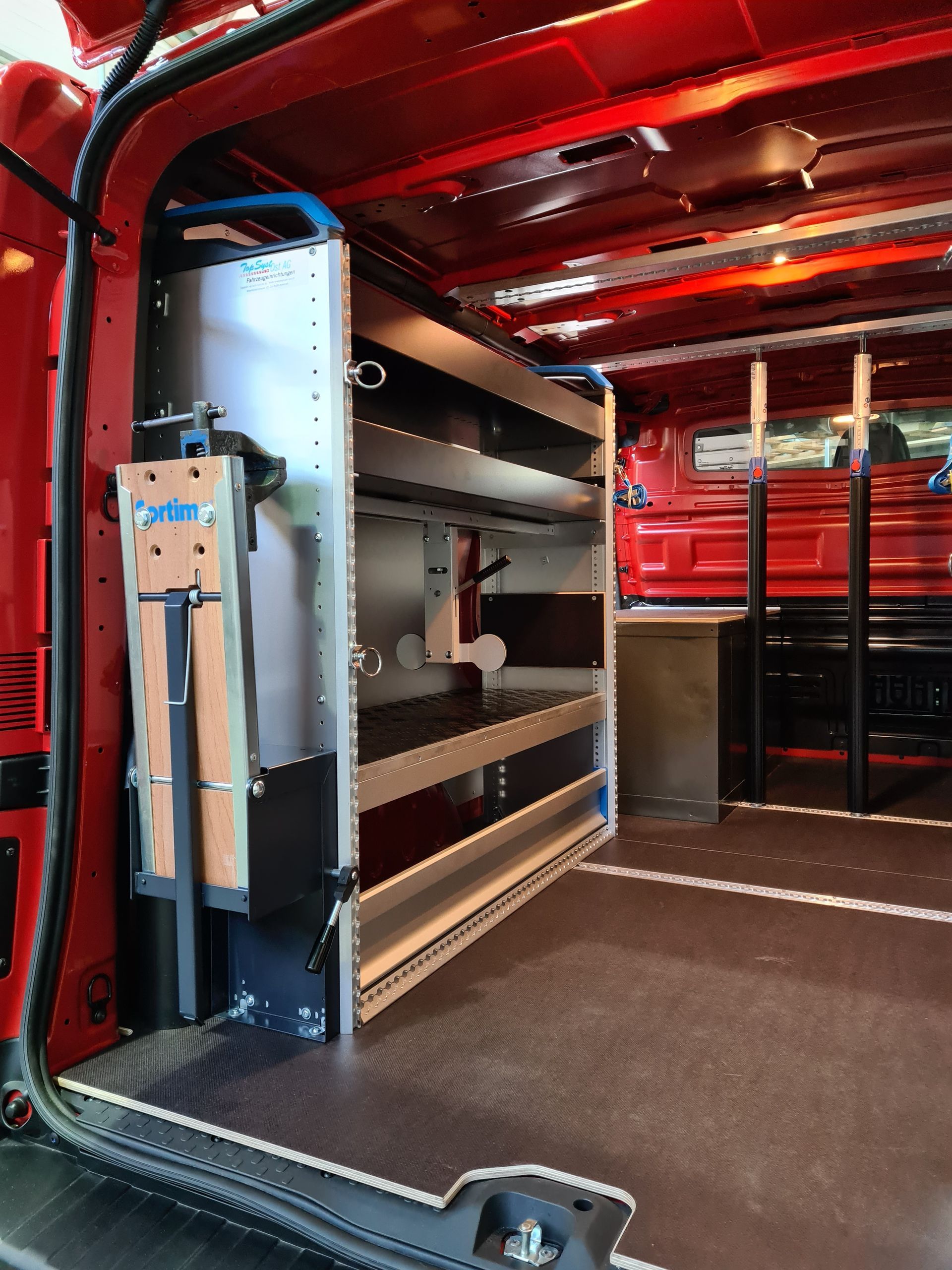Roter Van-Innenraum mit Metallregal. Schwarzer Boden und rote Wände sind sichtbar.