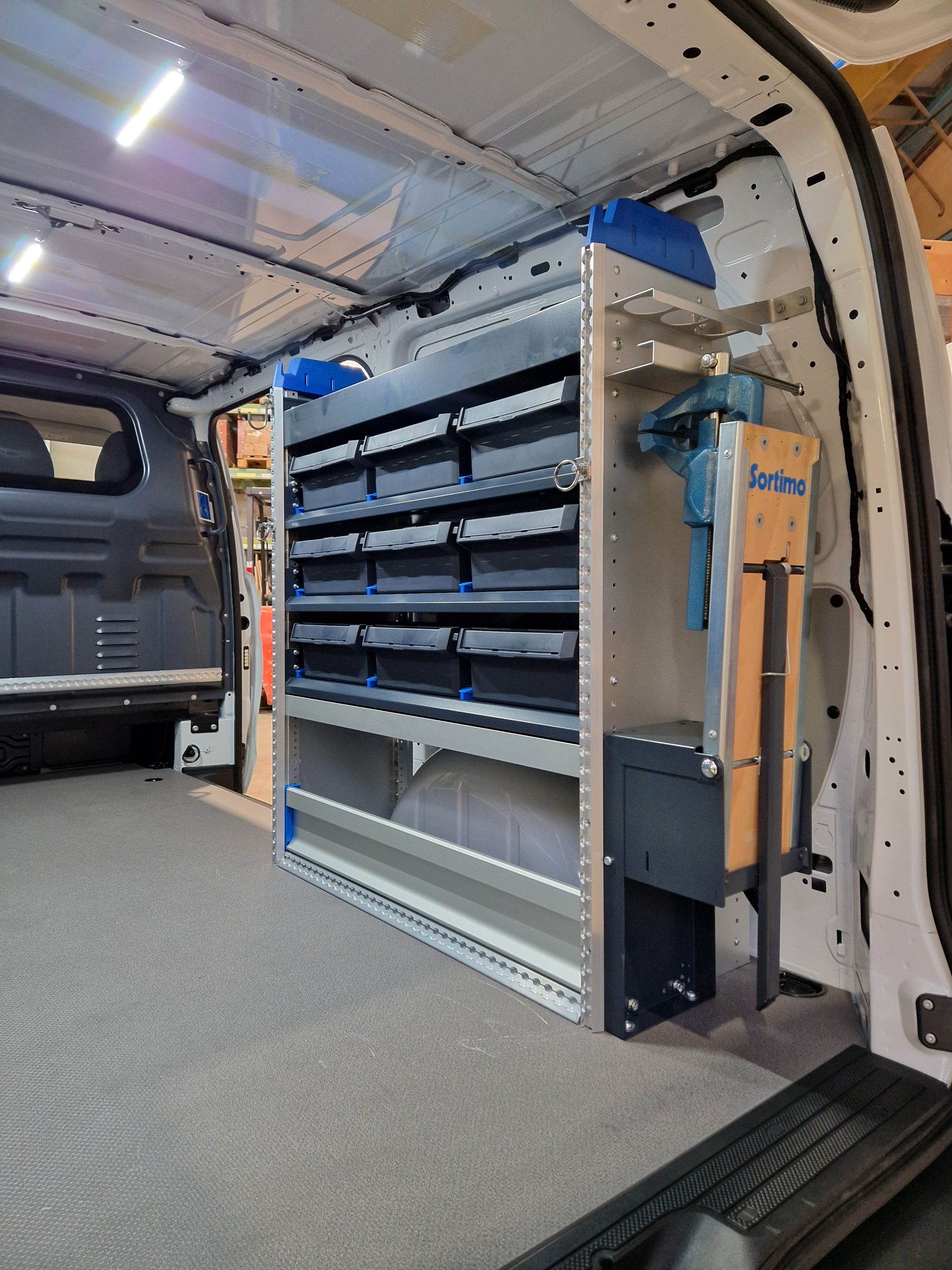 Innenraum eines weißen Lieferwagens mit maßgefertigten Regalen mit Schubladen und einem Werkzeugaufbewahrungssystem.