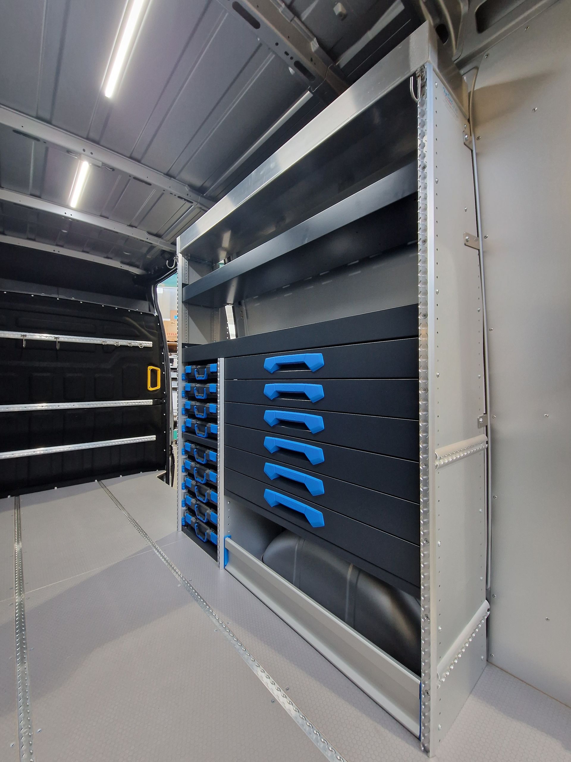 Innenraum eines Servicewagens mit Regalen und Schubladen für Werkzeuge und Ausrüstung, grau und blau.