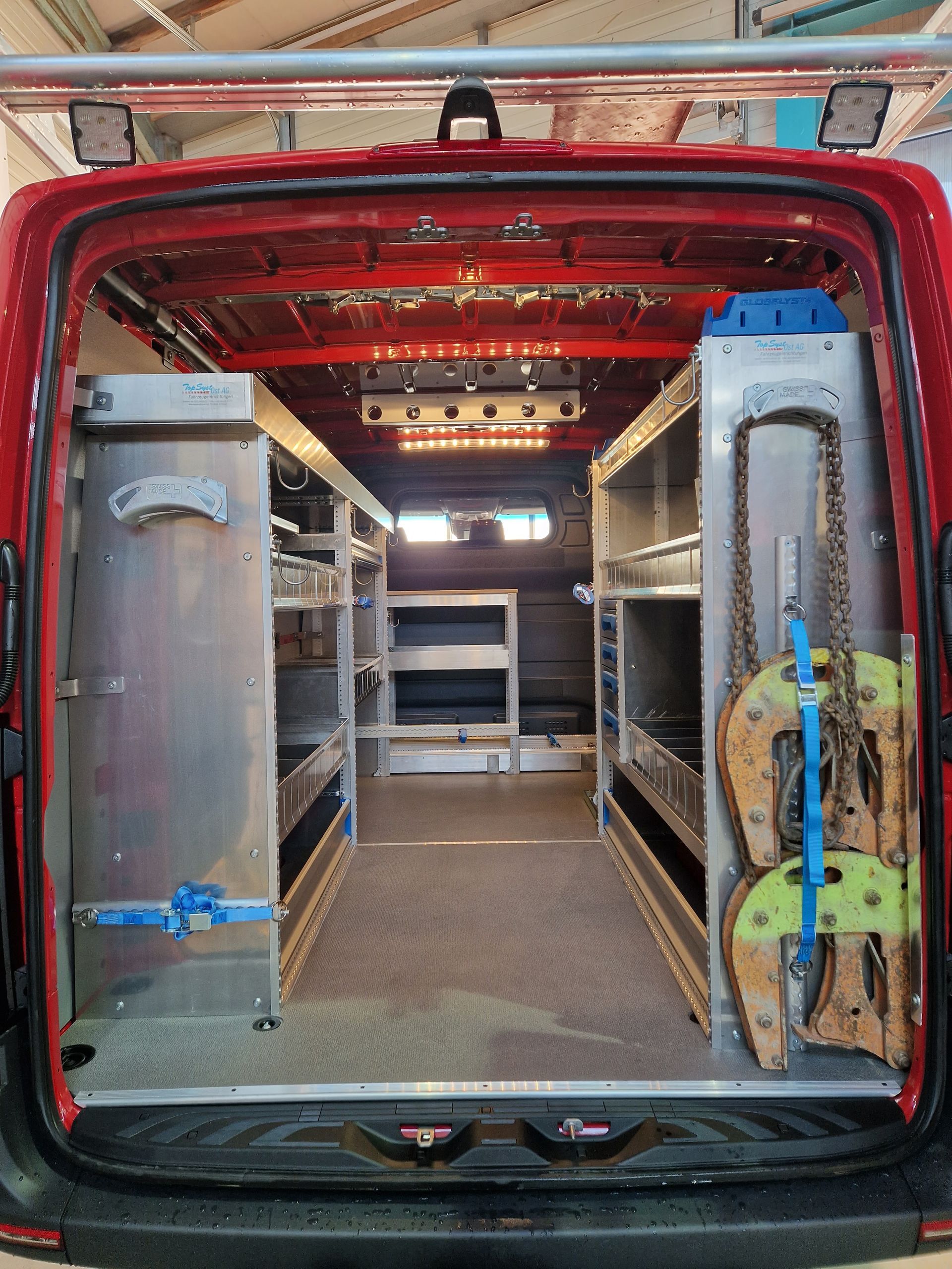 Innenraum eines roten Nutzfahrzeugs mit Regalen und Ausstattung aus Aluminium.