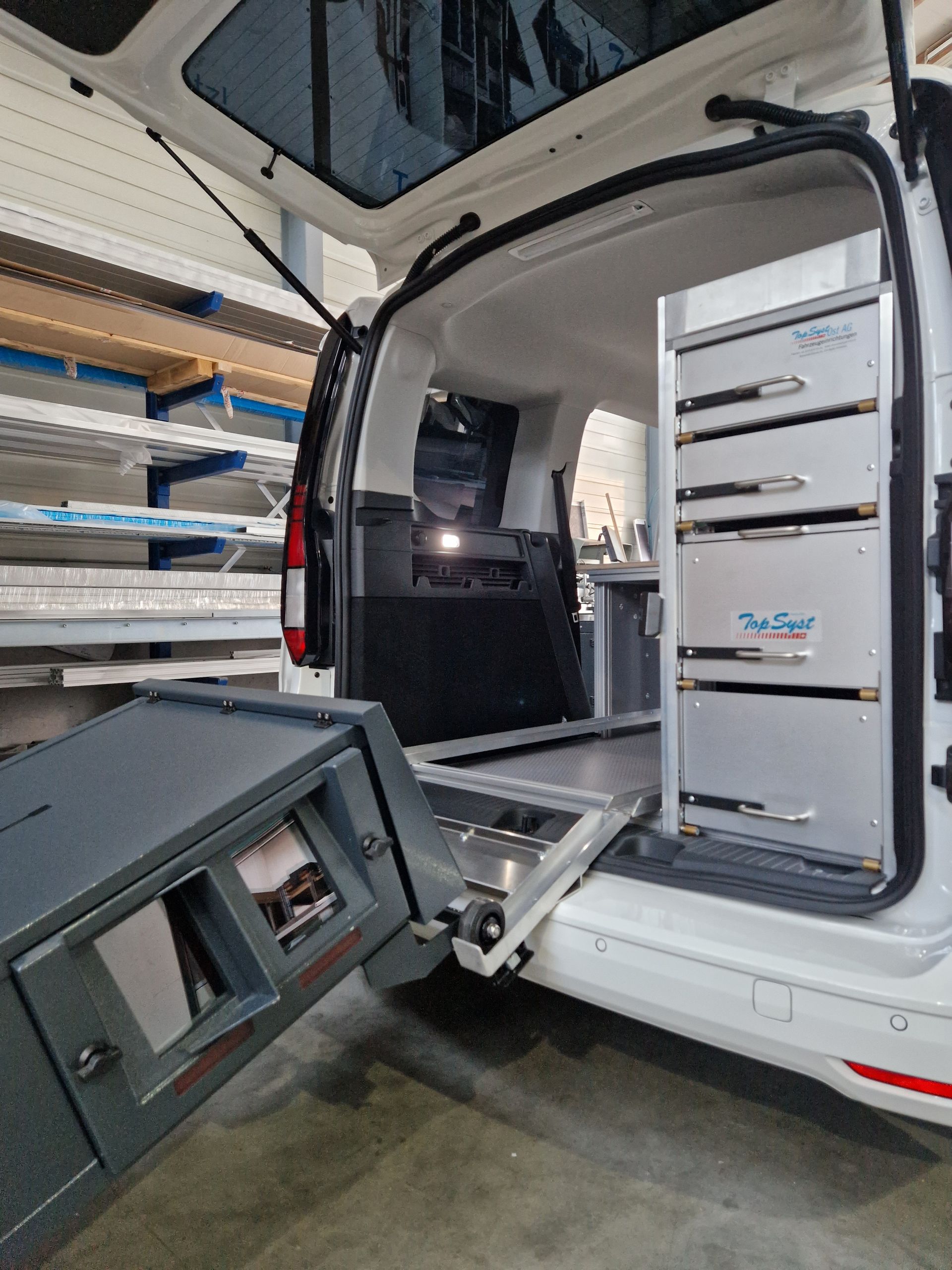 Weißer Van-Innenraum mit Aufbewahrungsschubladen und ausziehbarem Kochbereich.