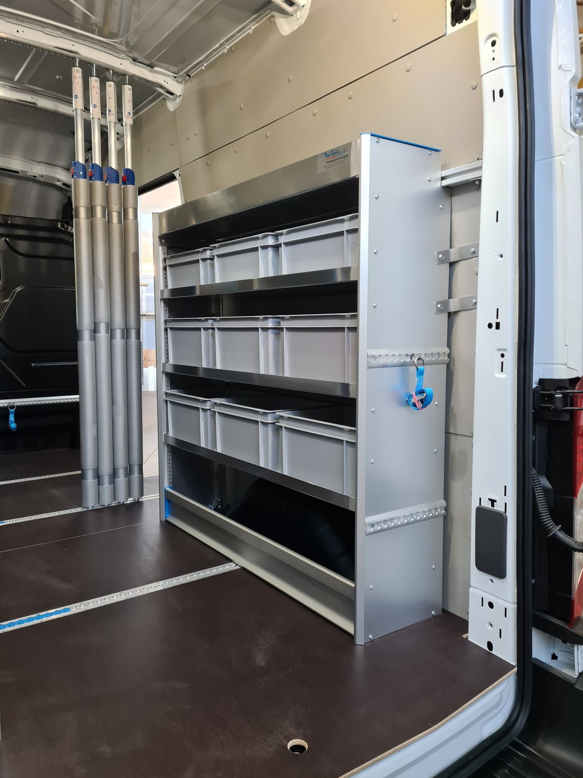 Im Inneren eines Lieferwagens: Metallregal mit mehreren Behältern und Stauraum.