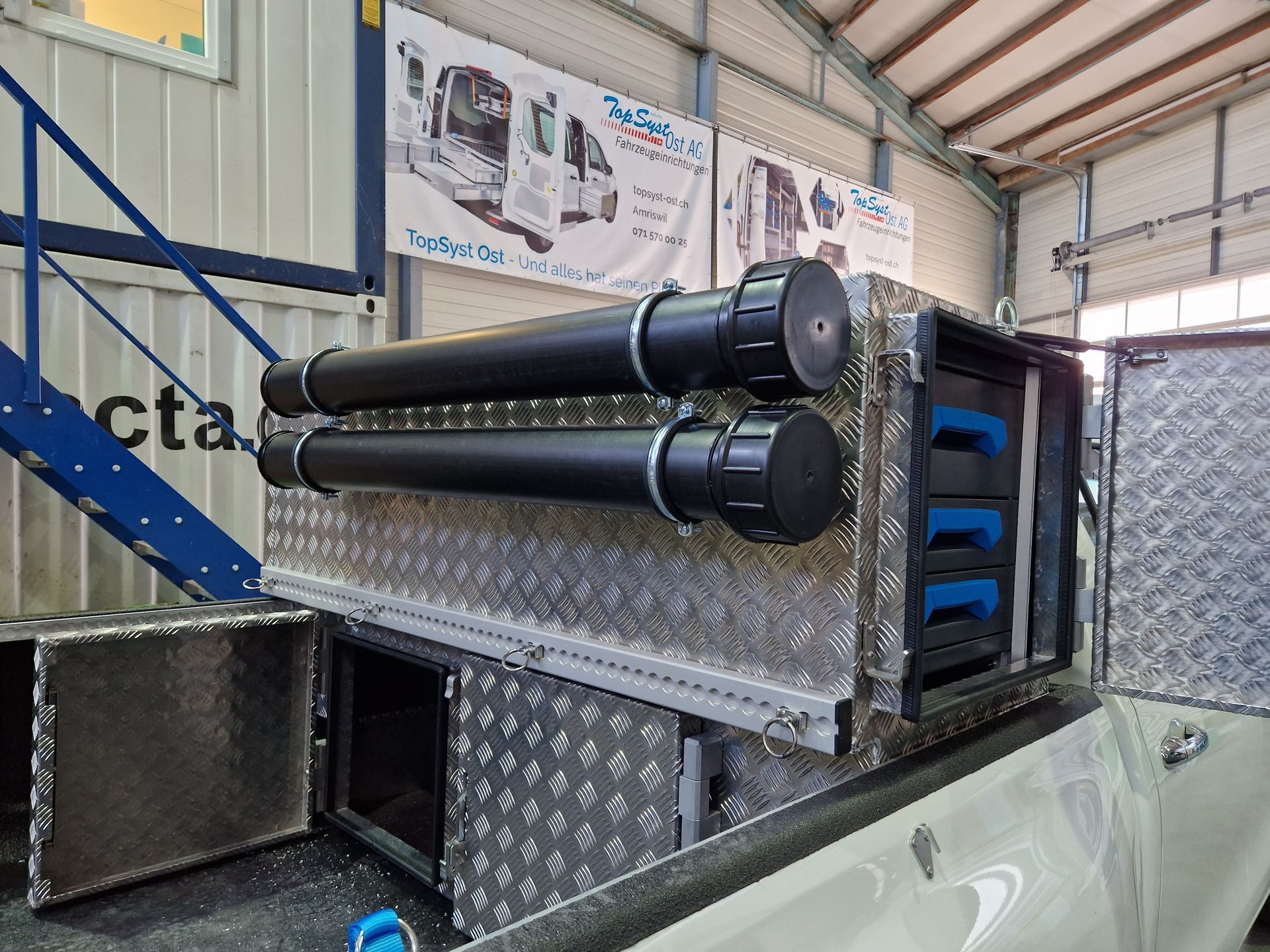 Aluminium-Ladeflächenaufbewahrung mit schwarzen Rohren und Schubladen, im Innenbereich.