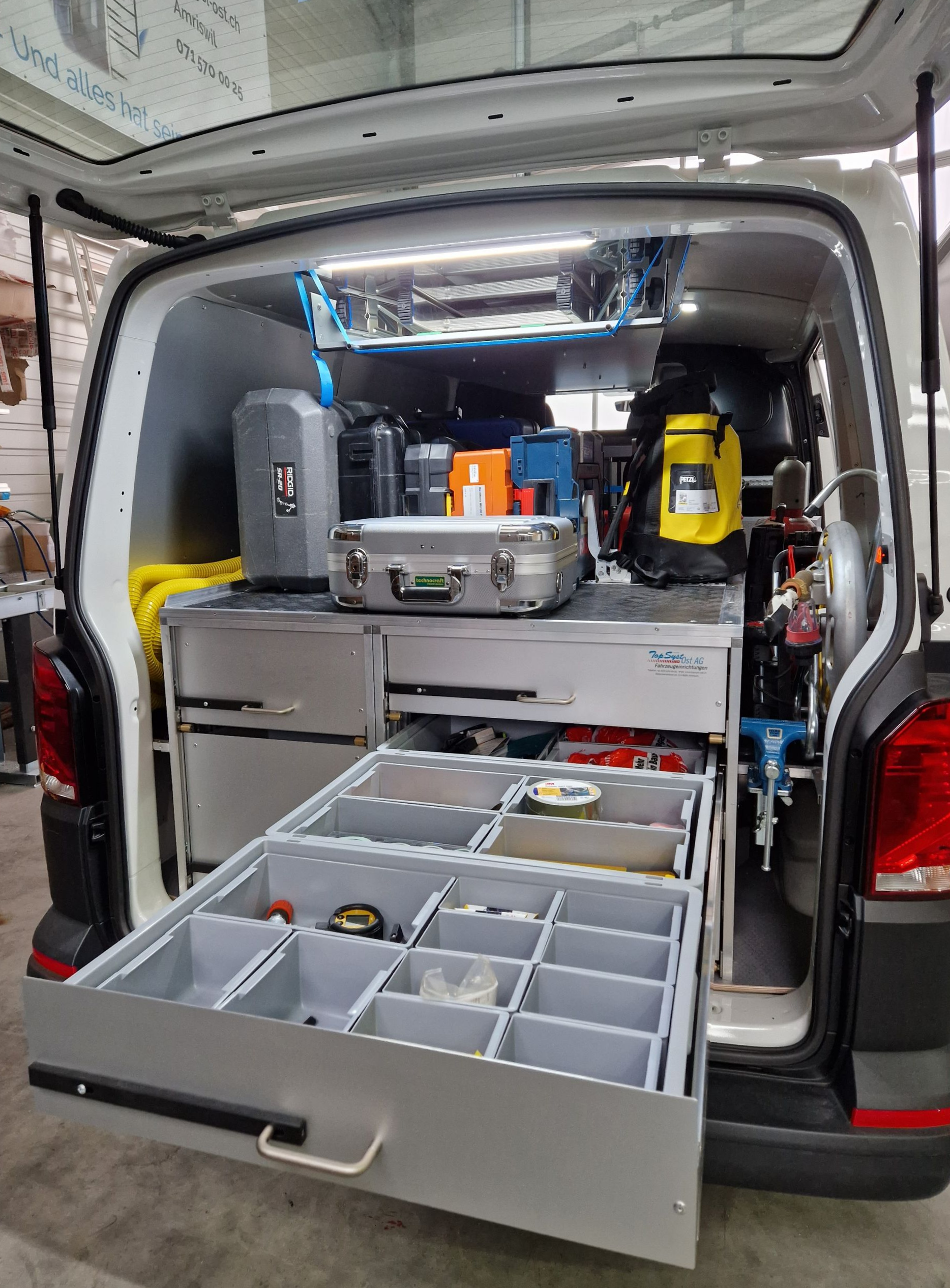 Im Inneren eines weißen Servicewagens sind die Schubladen geöffnet und mit Werkzeugen und Teilen gefüllt.