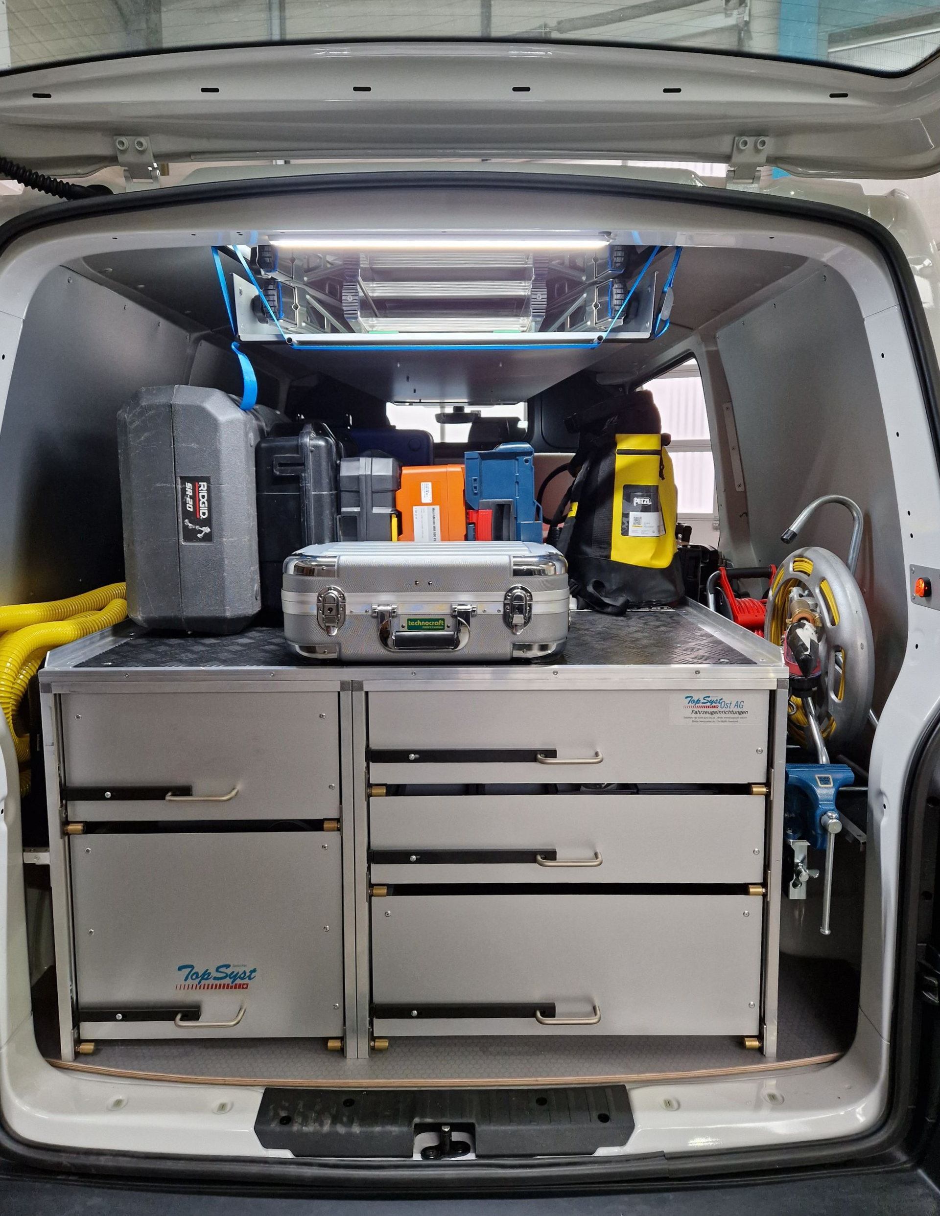 Innenraum eines Servicewagens mit Werkzeugen und Geräten, die in Schubladen und auf Regalen aufbewahrt werden.