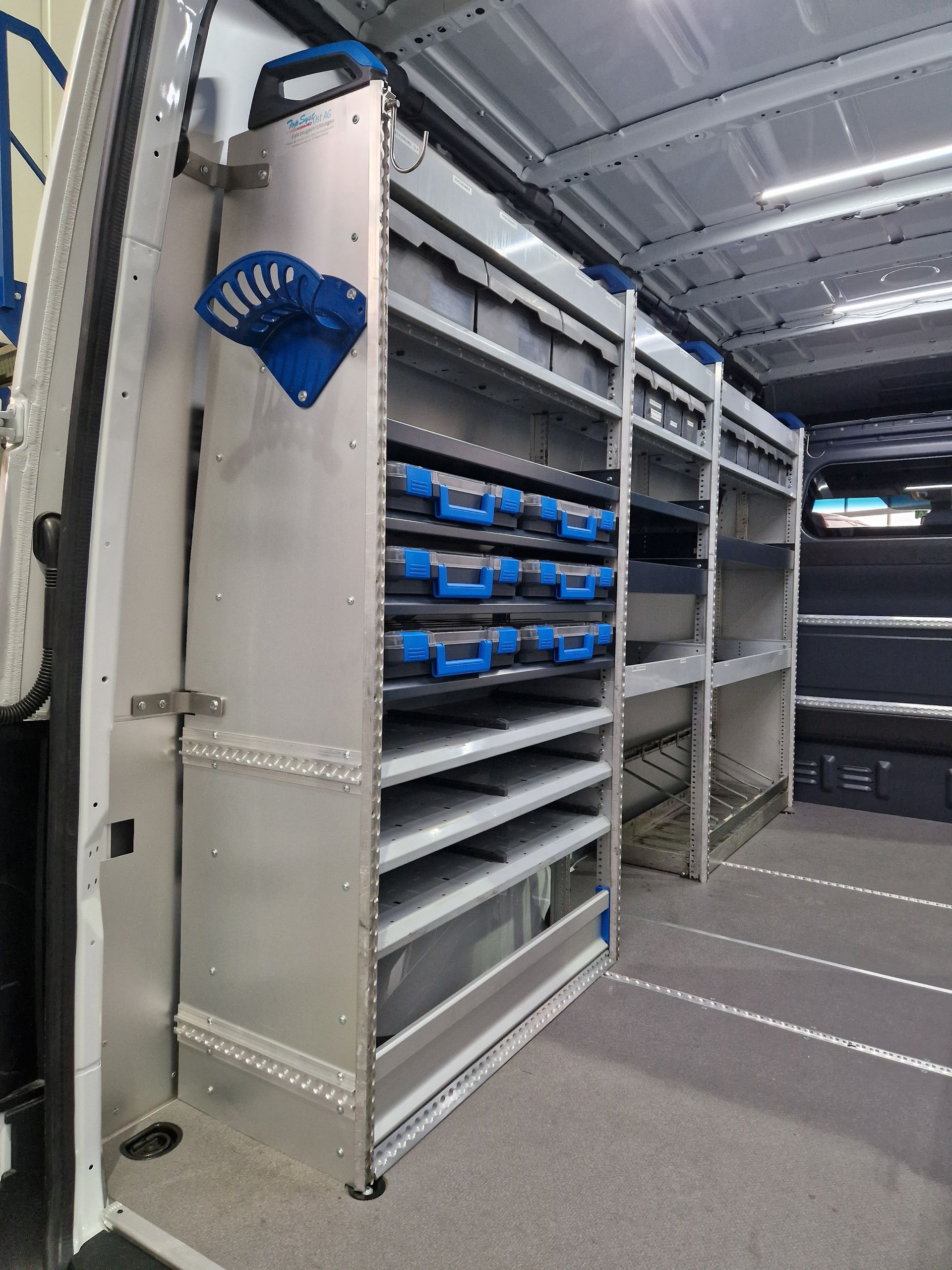 Innenausstattung des Lieferwagens mit Metallregal und blauen Behältern.