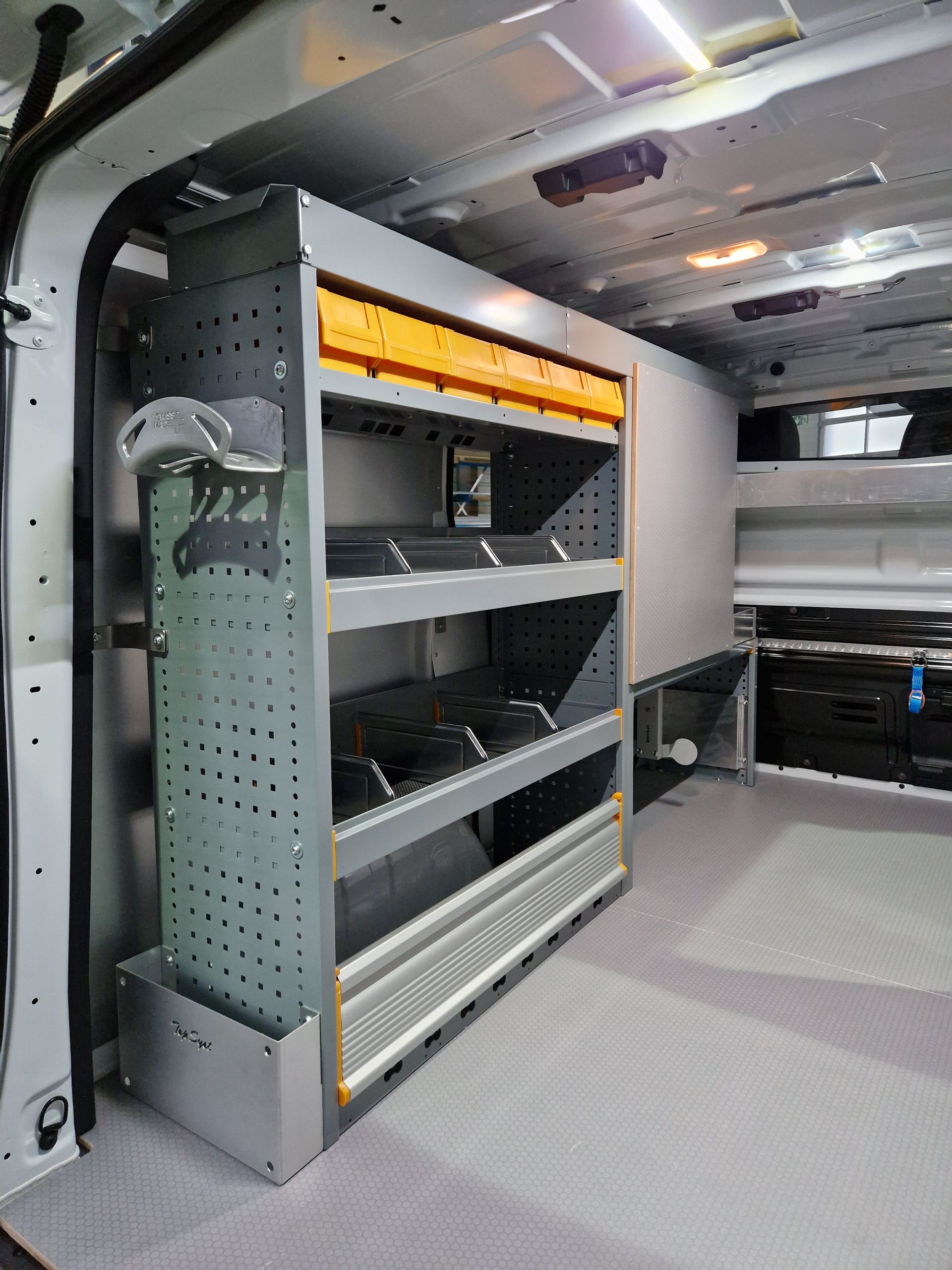 Innenansicht eines Lieferwagens mit Metallregal; grau, orange und silber.