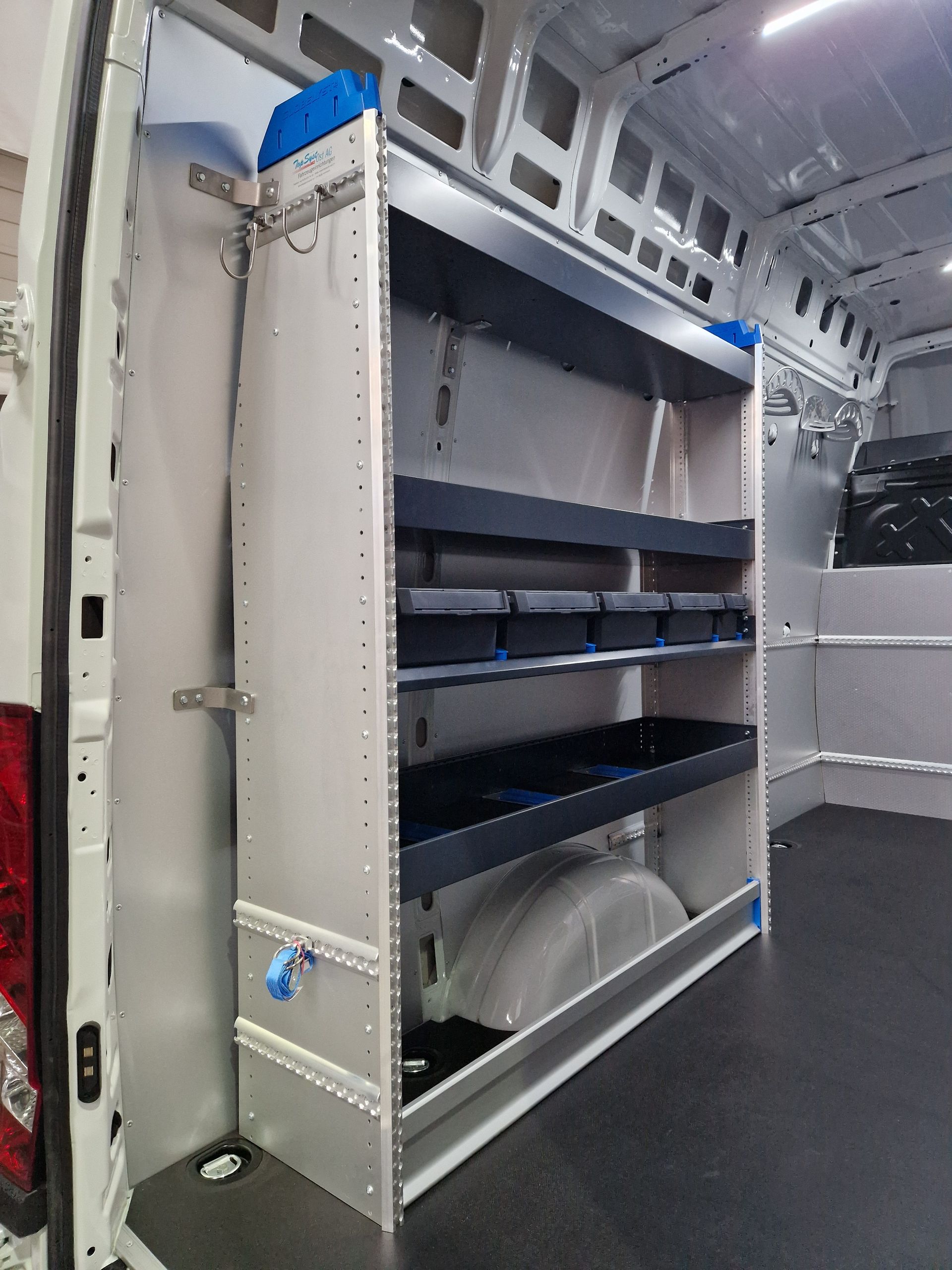 Innenraum eines weißen Lieferwagens mit Regaleinheit. Die Regale enthalten Lagerbehälter.