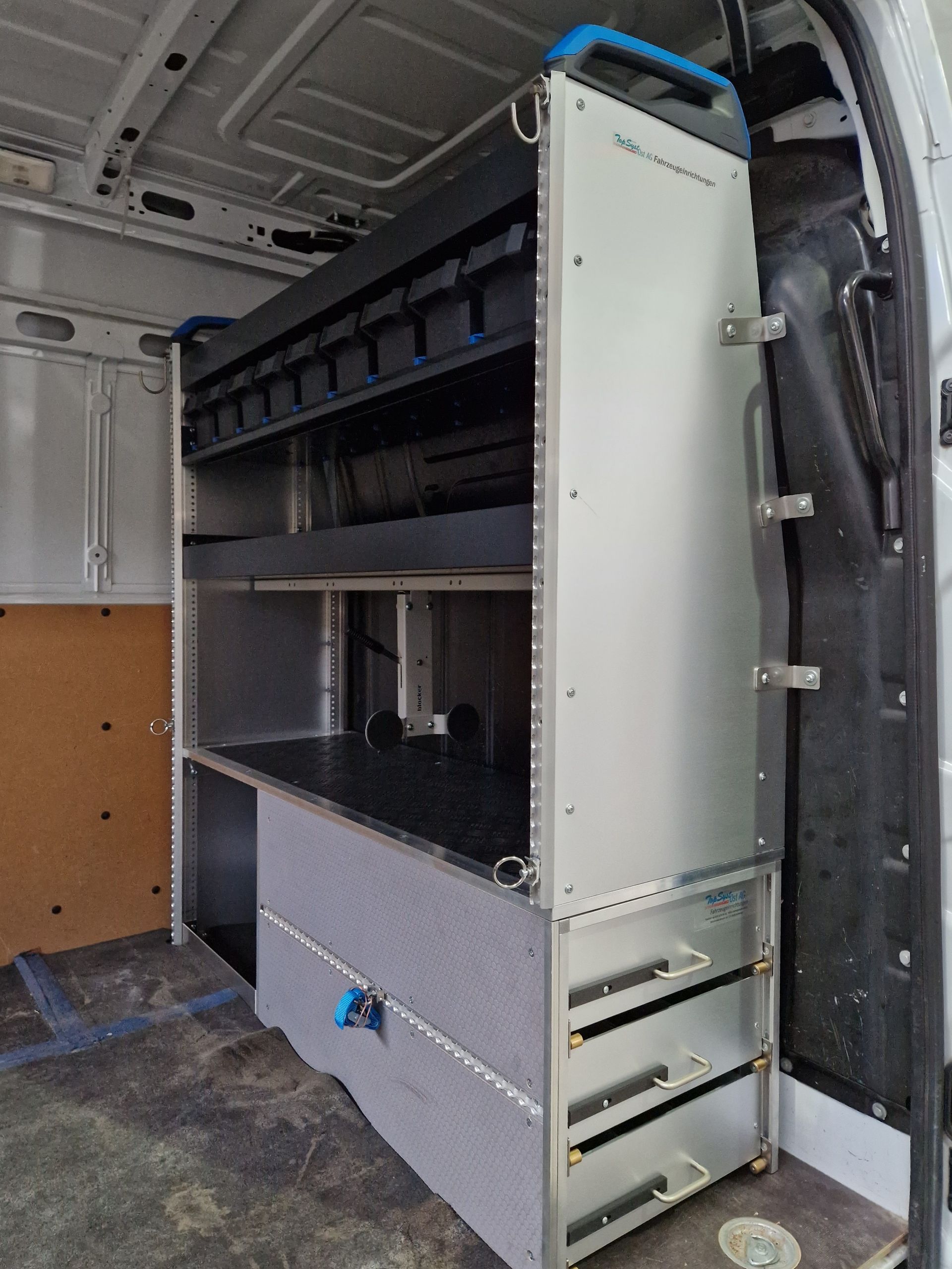 Innenraum eines weißen Lieferwagens mit eingebautem Metallregal mit Schubladen und Regalen.