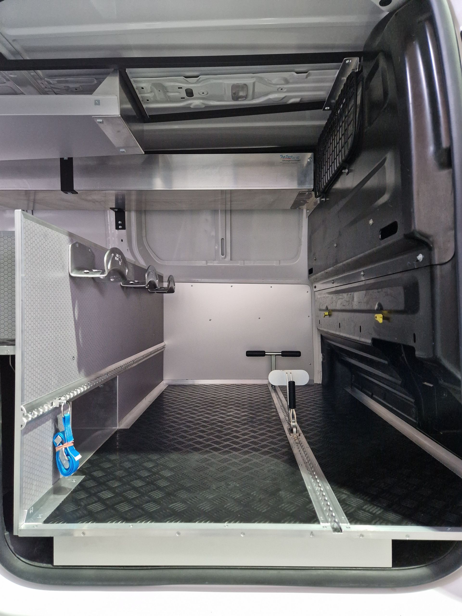 Innenraum eines weißen Lieferwagens, ausgestattet mit Metallregalen und Stauraum.