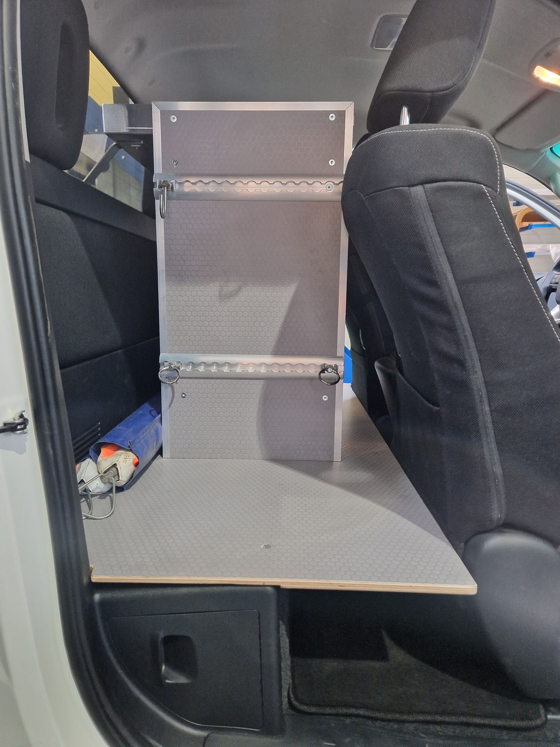 Innenausstattung des Wagens mit einem maßgefertigten Stauraum zwischen den Sitzen, graues Sperrholz, schwarze Stoffsitze.