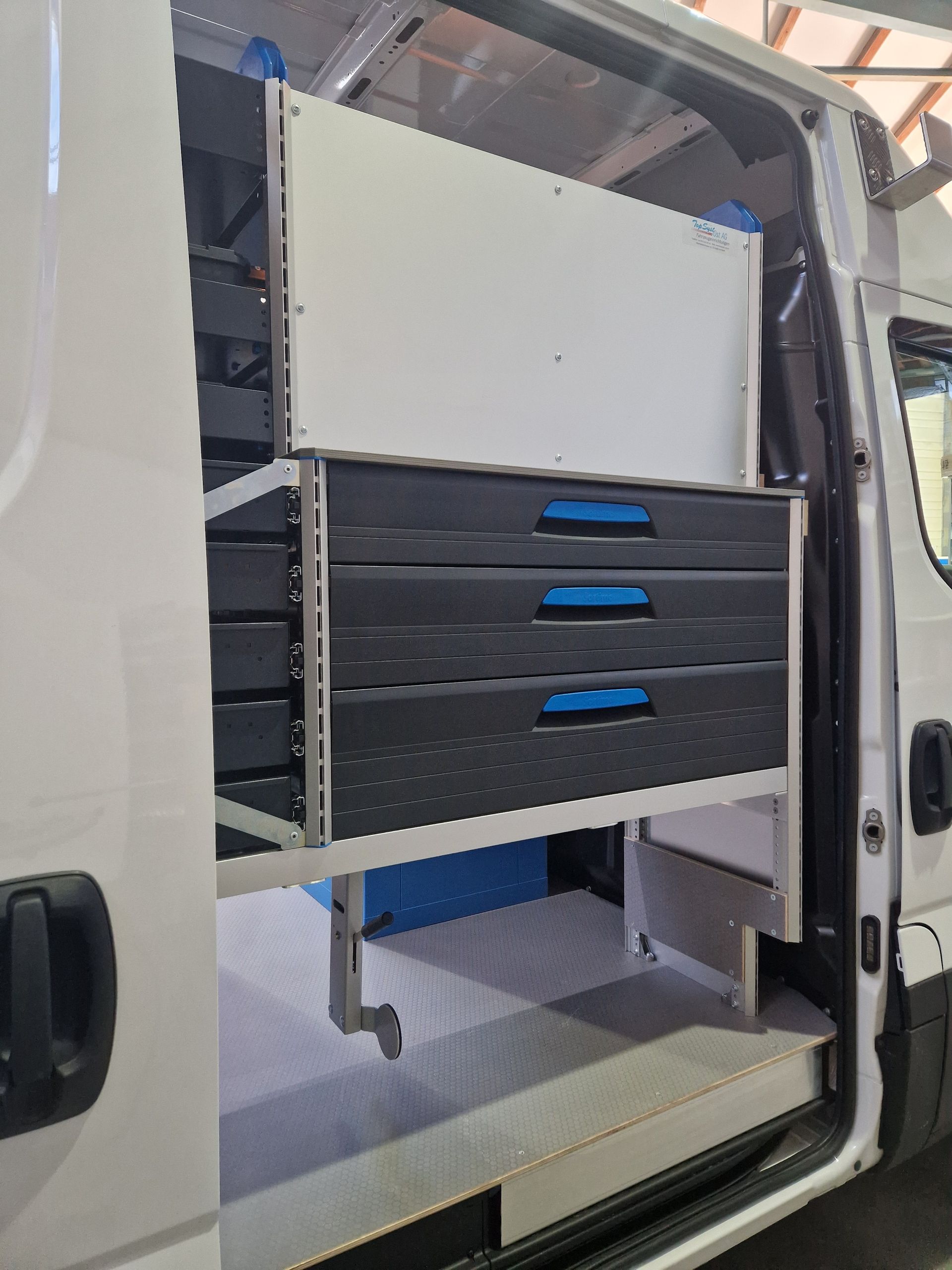 Weißer Van-Innenraum mit eingebauten Schubladen und Regalen.