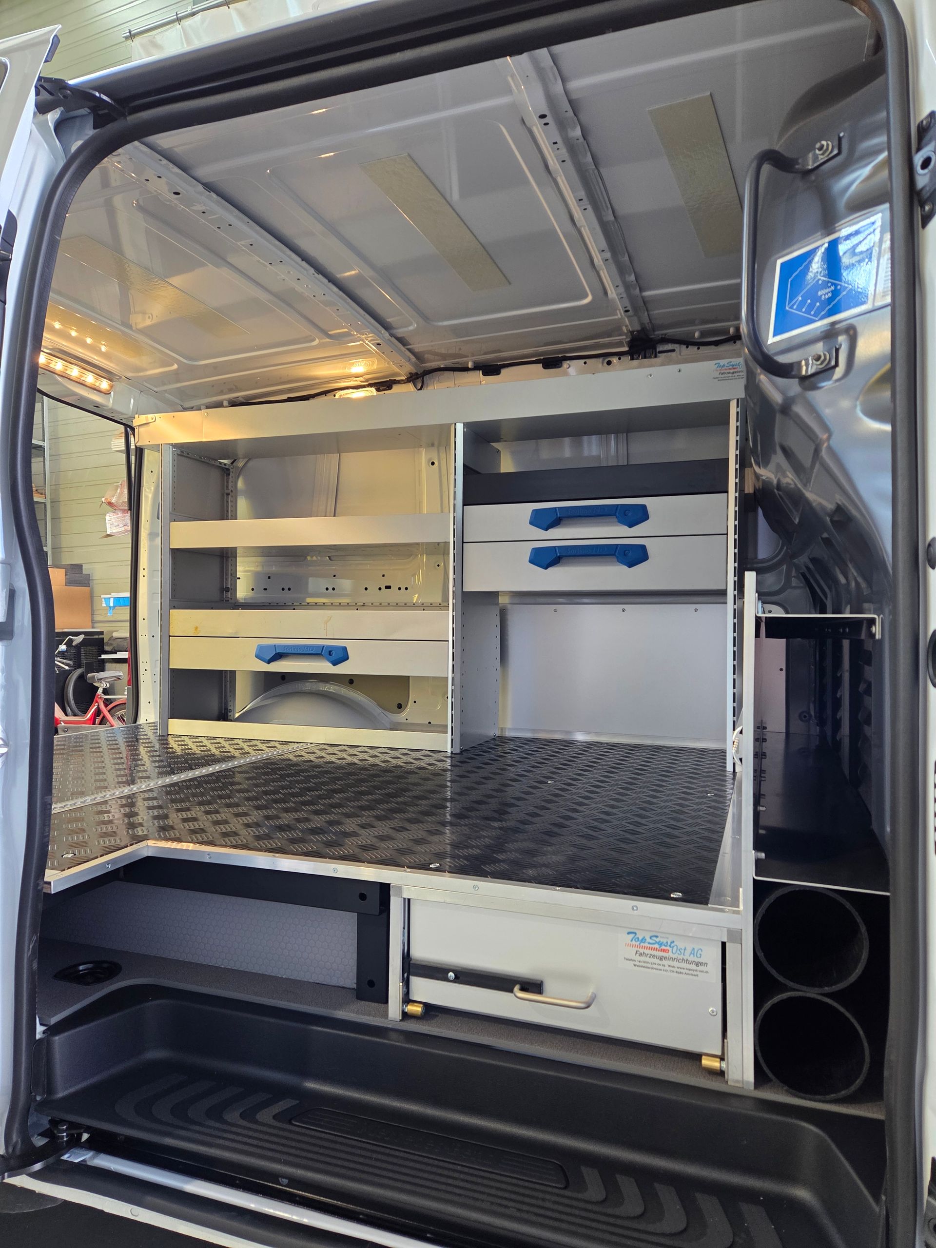 Innenraum eines Arbeitstransporters mit Regalen, Schubladen und Staufächern, überwiegend grau.