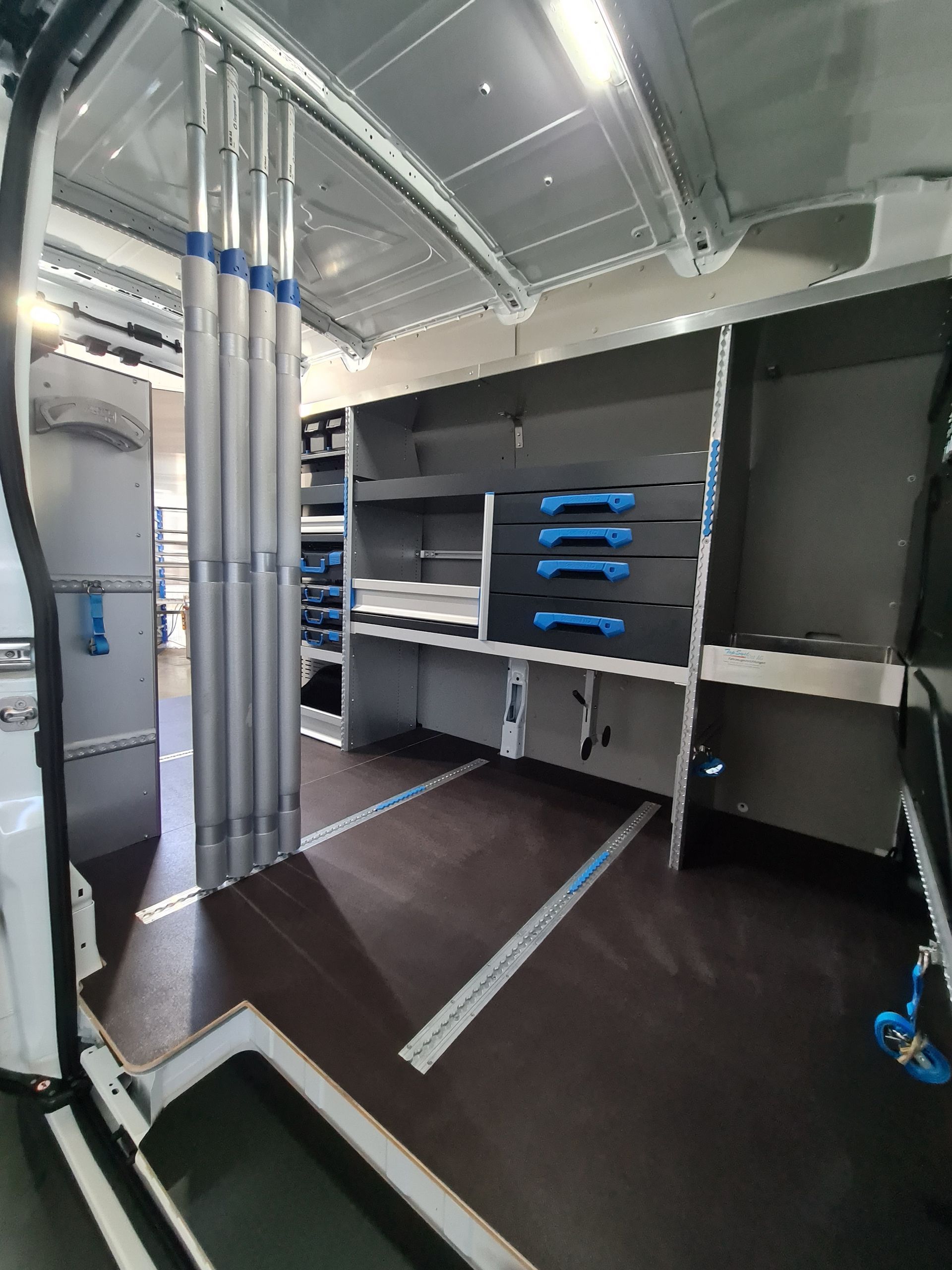 Innenraum eines Lieferwagens mit Regalen, Schubladen und vertikaler Lagerung für Werkzeuge und Ausrüstung.