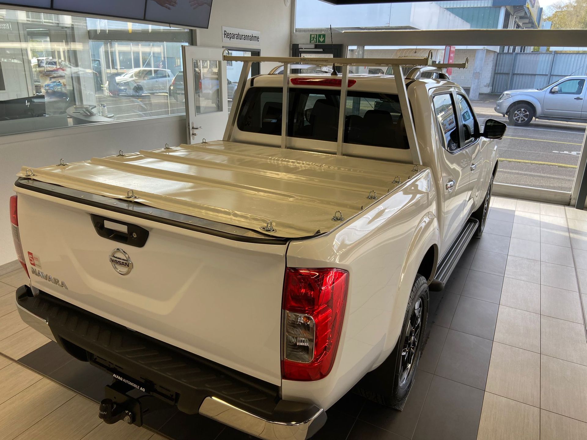 Weißer Nissan-Pickup mit Gepäckträger in einem Ausstellungsraum.